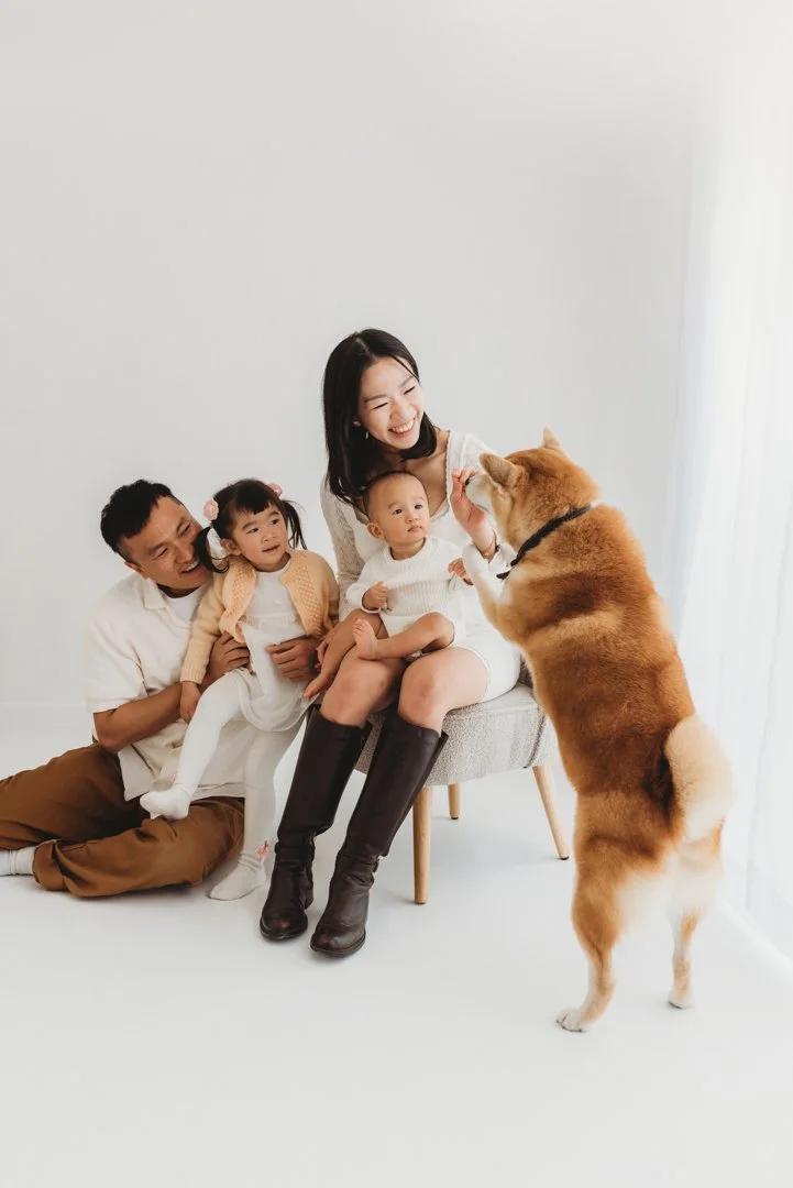Happy Asian family with two young children and a dog in a bright white room