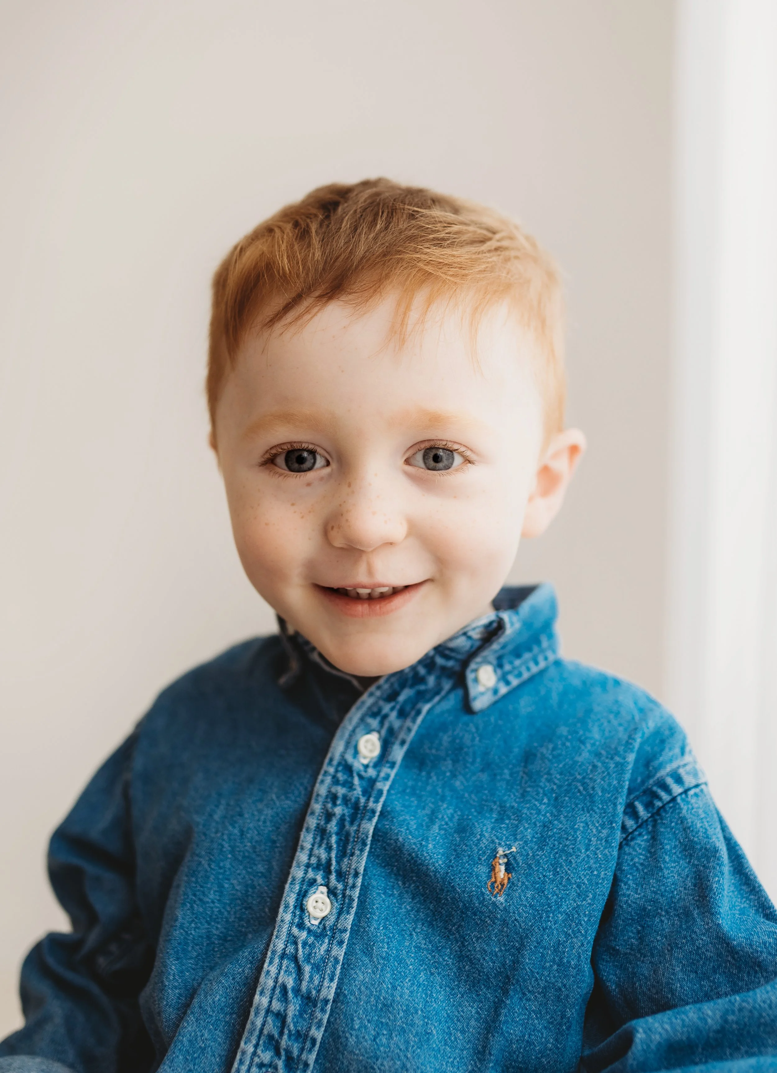 naturally lit portraits of a little boy looking straight at the camera with a smile on his face