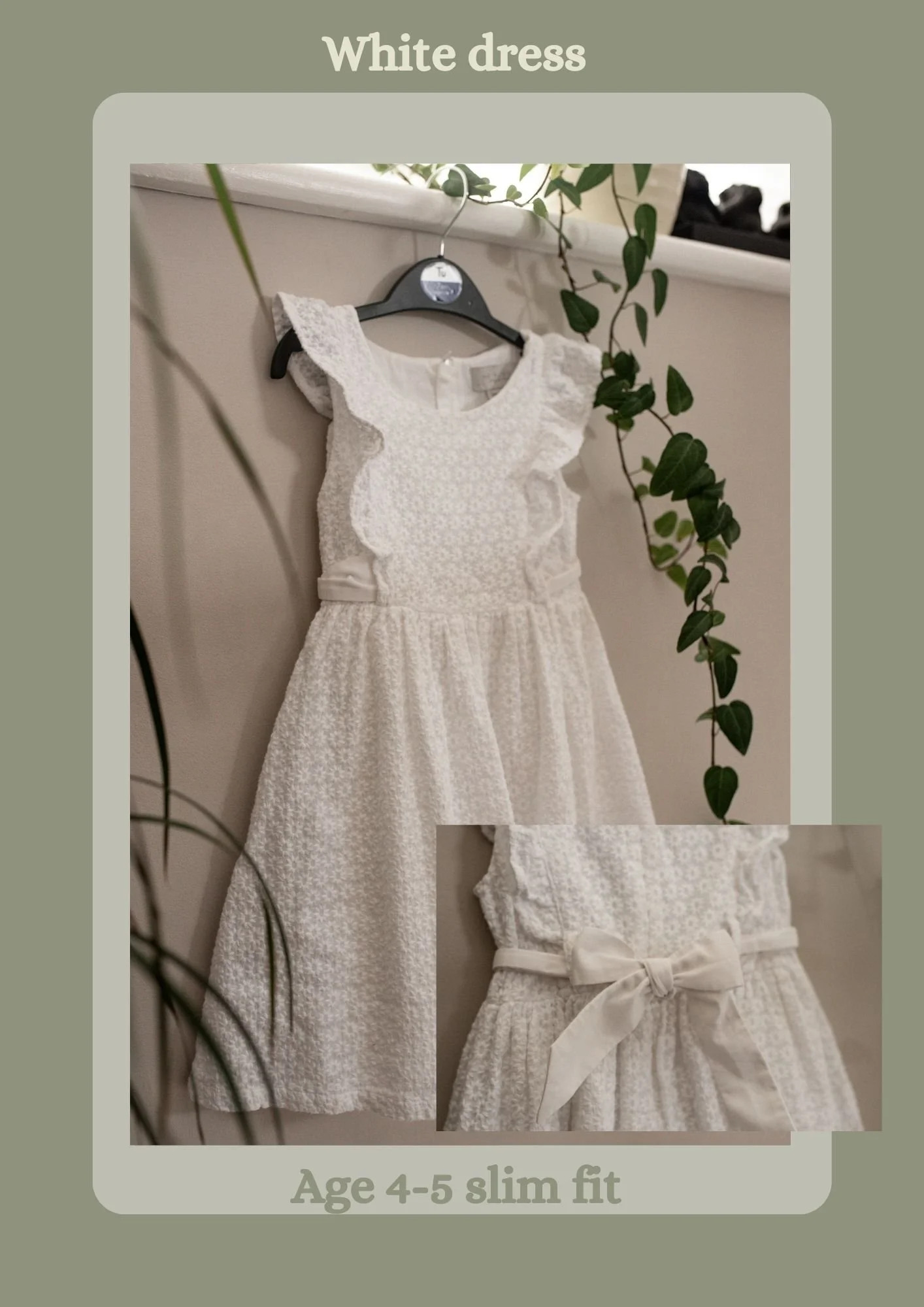 A white dress for girls aged 4 to 5 with a slim fit, featuring ruffled sleeves, textured fabric, and a bow at the waist, hanging on a black hanger against a white wall with green plants nearby.