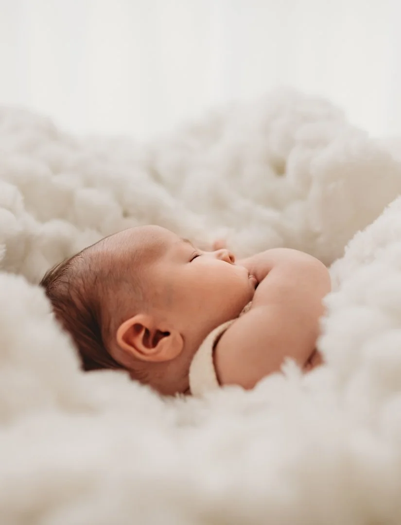 Sleeping Newborn wrapped in soft blankets at newborn photoshoot in Saffron Walden Essex.
