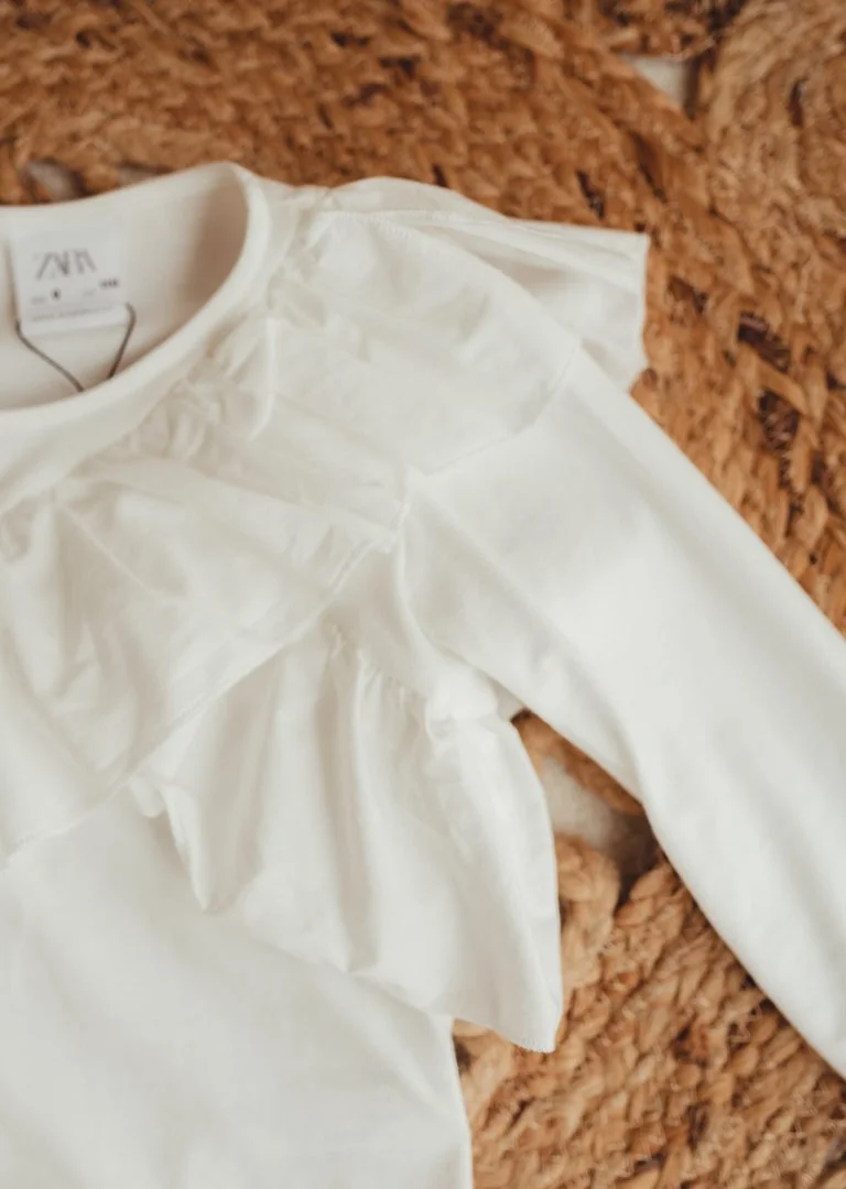 A white V-neck long-sleeve shirt lying on a textured brown surface.
