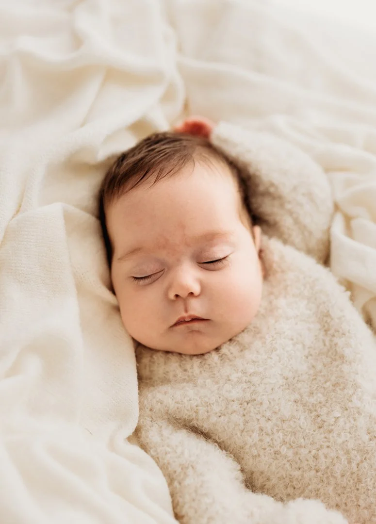 Sleeping baby in a fluffy cream jumper in a natural sleeping position at a studio photoshoot in Saffron Walden Essex by Jodie Wilson Photosgraphy