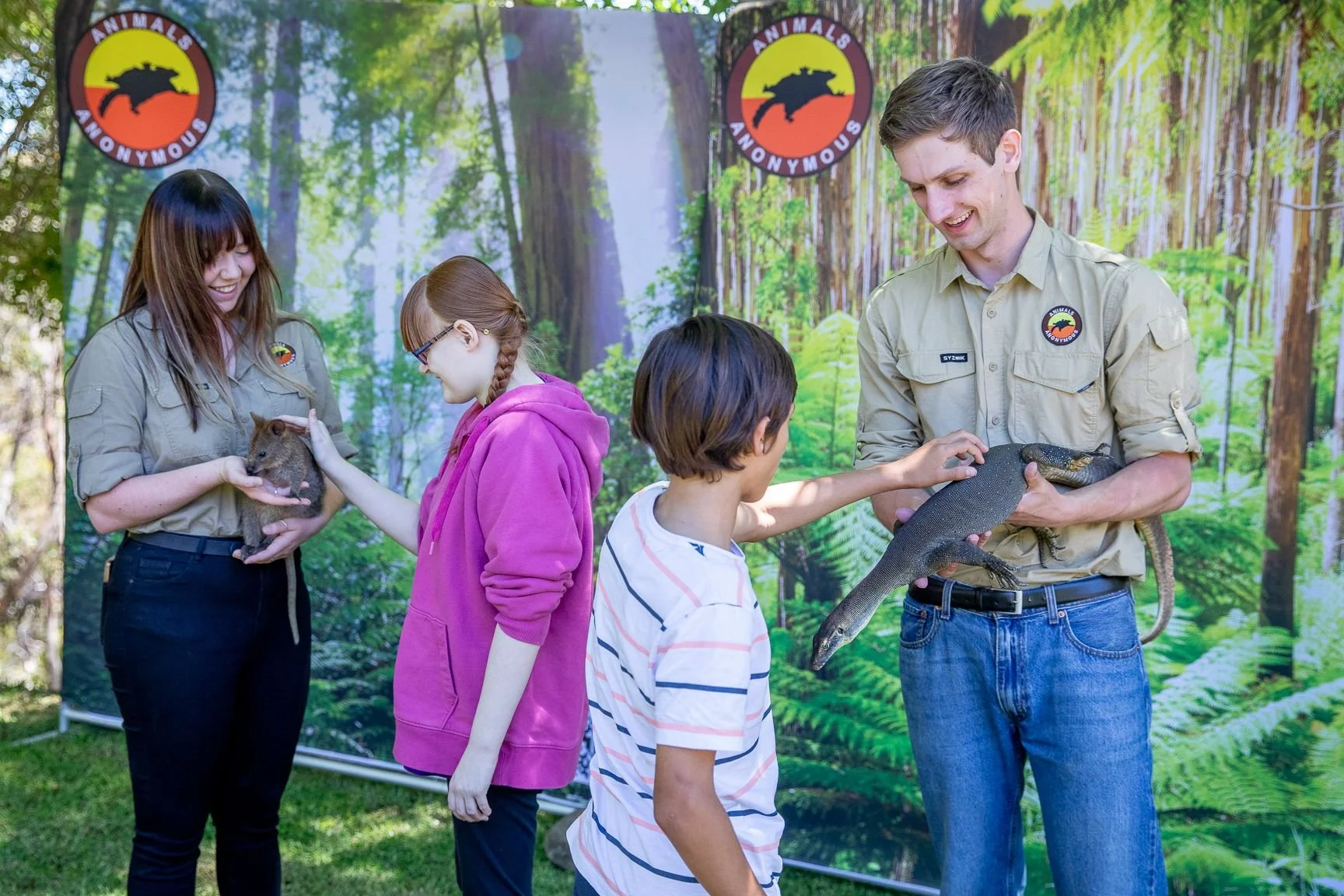 Group of children and adults interacting with animals at an educational event about wildlife.