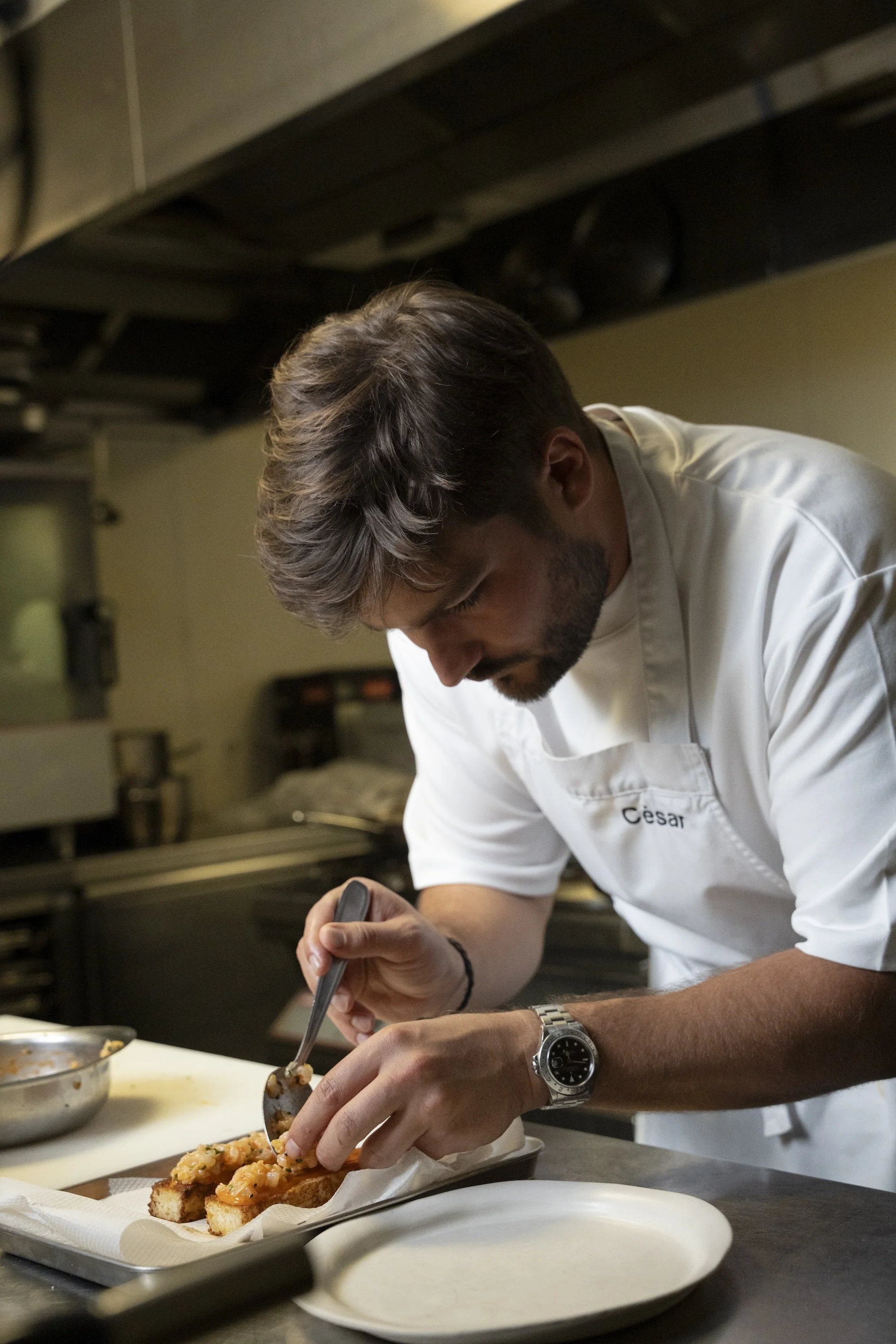 A chef adding toppings to a dish in a professional kitchen