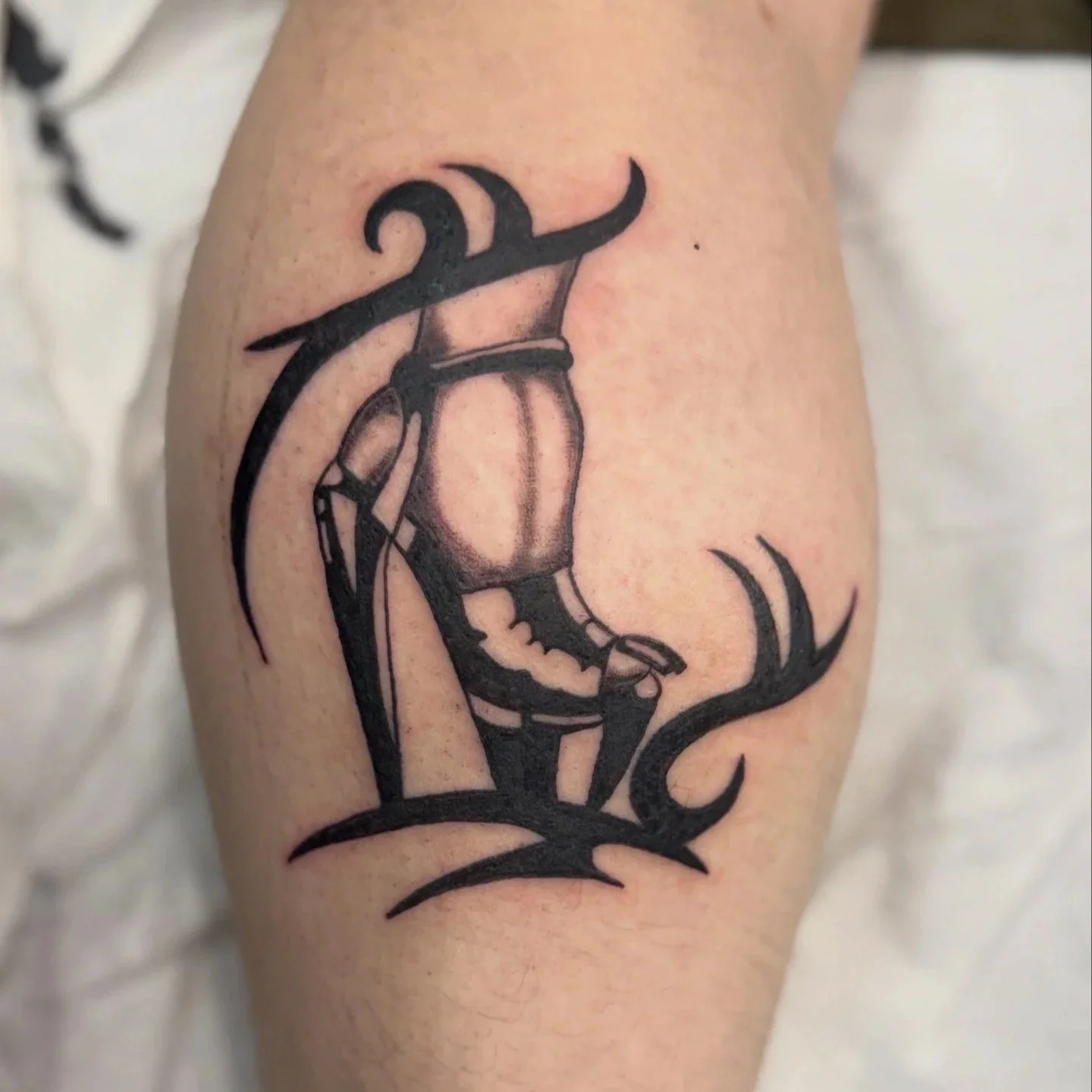 Black tattoo of a stag with large antlers, with shading details on the face and neck, on a person's arm.