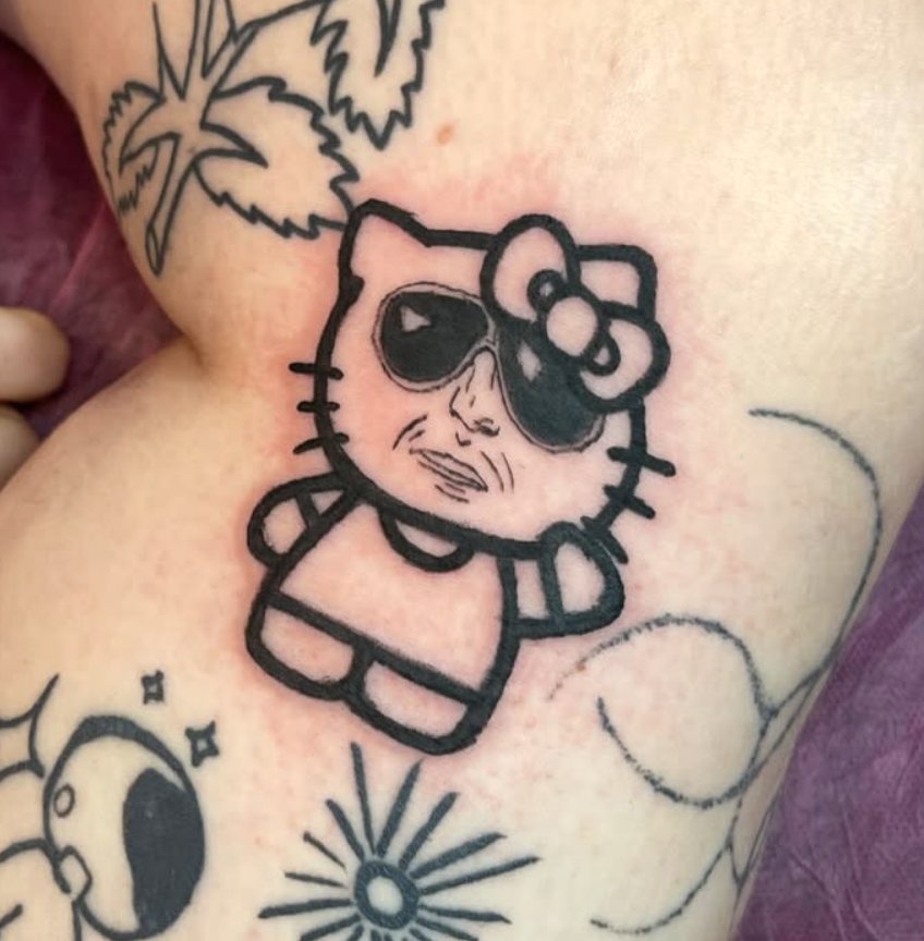Tattoo of Hello Kitty with sunglasses and a bow, with some surrounding sketches of a leaf and a sun.