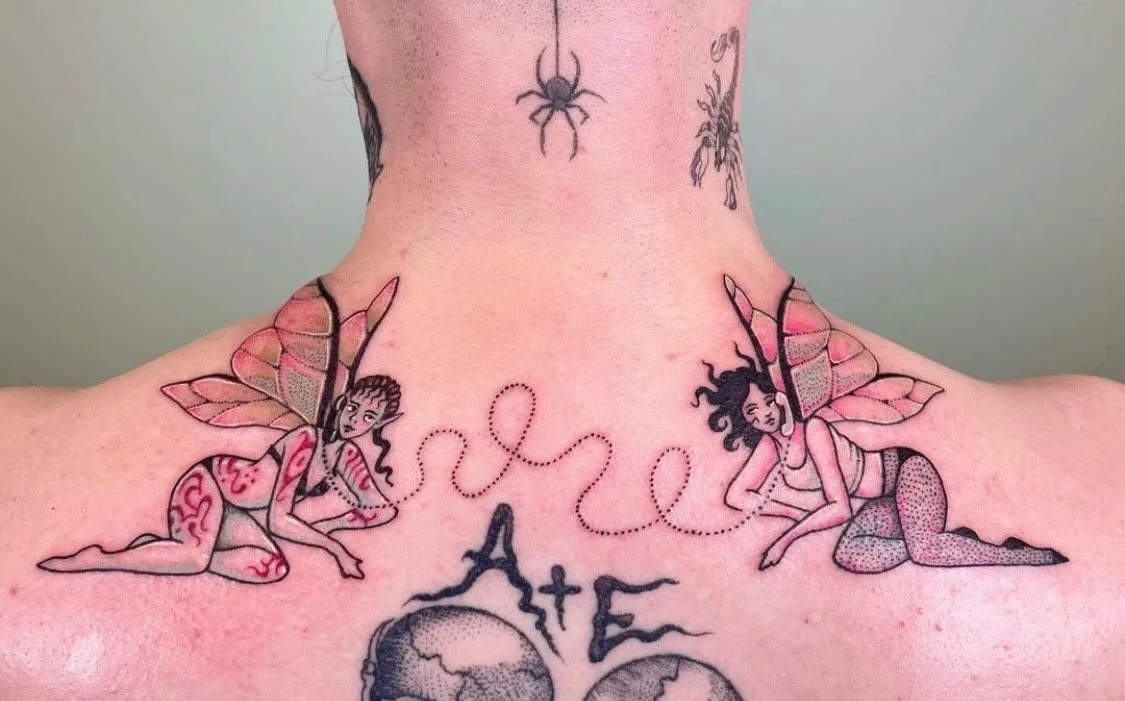 Tattoo of two fairy-like women with butterfly wings connected by a dotted line in cursive, with the words 'love' and 'Art' below.
