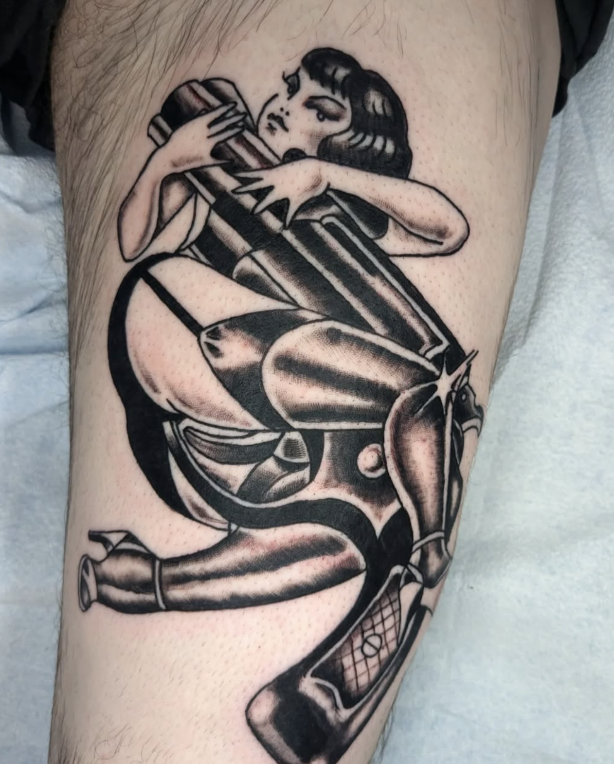 A black and gray tattoo of a woman holding a large lipstick, with a martini glass and fishnet gloves adding vintage pin-up style elements.