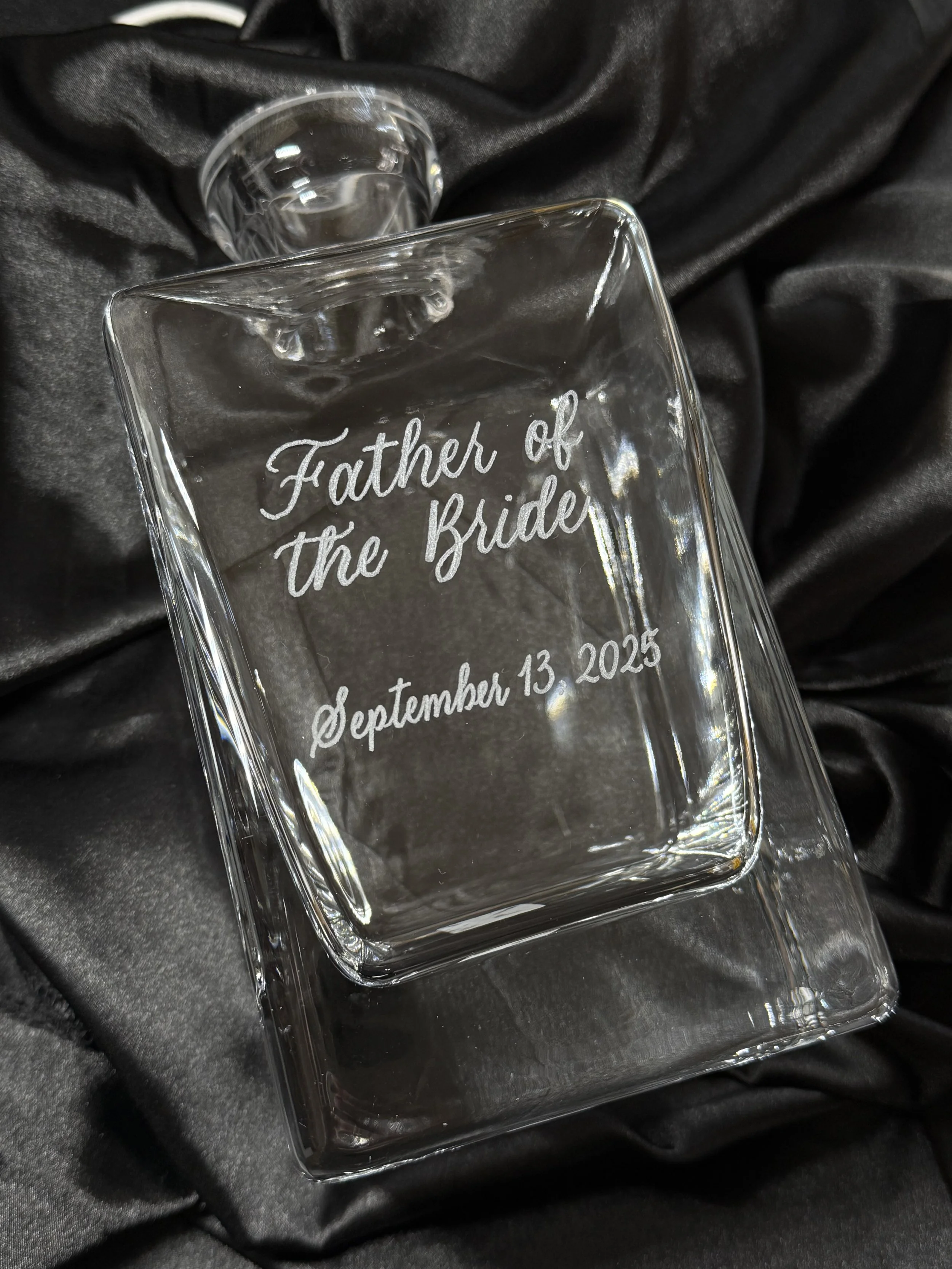 glass decanter Father of the Bride with date, on a black satin background