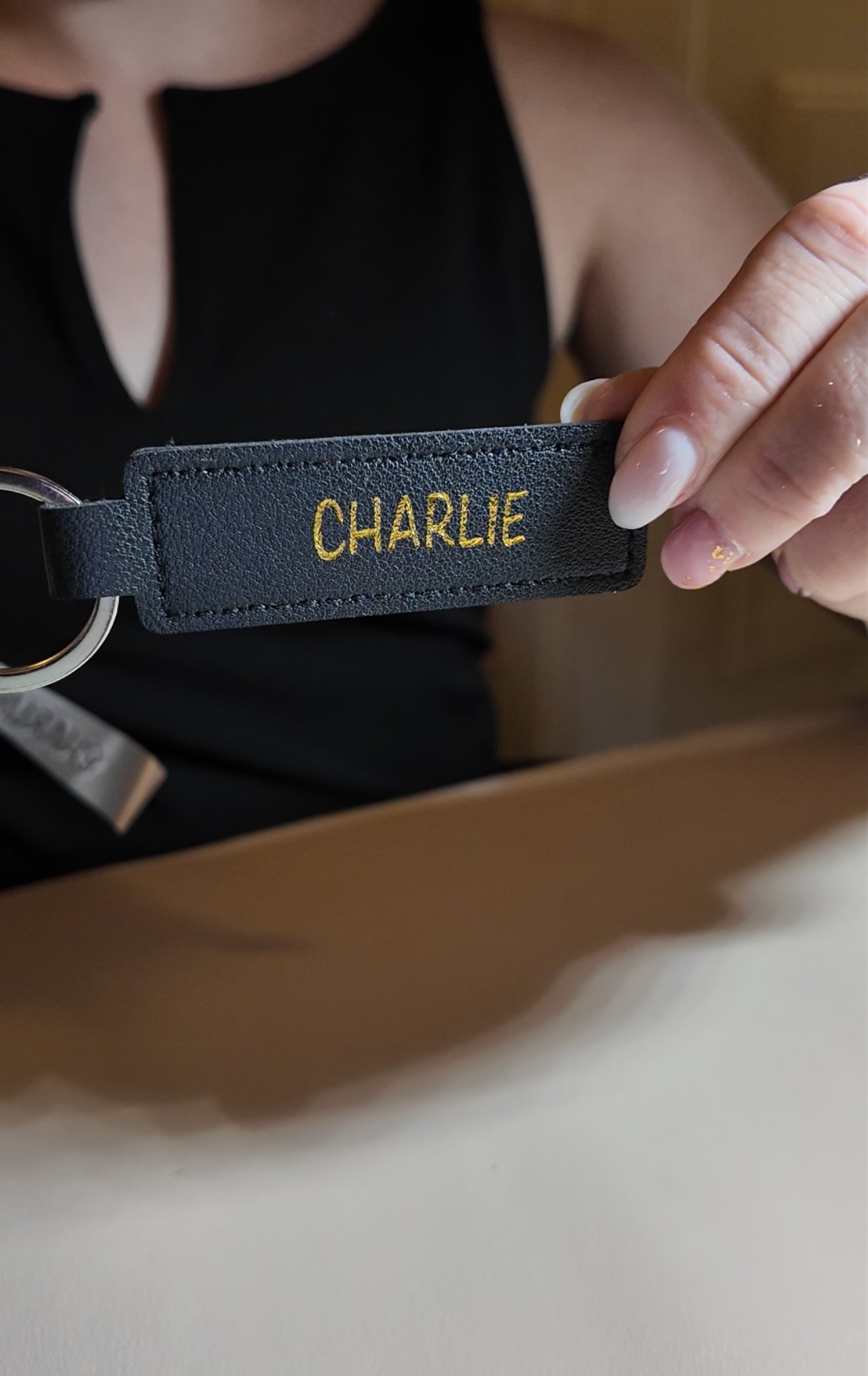 black rectangular keychain personalized with the name "CHARLIE" in all caps with gold writing 