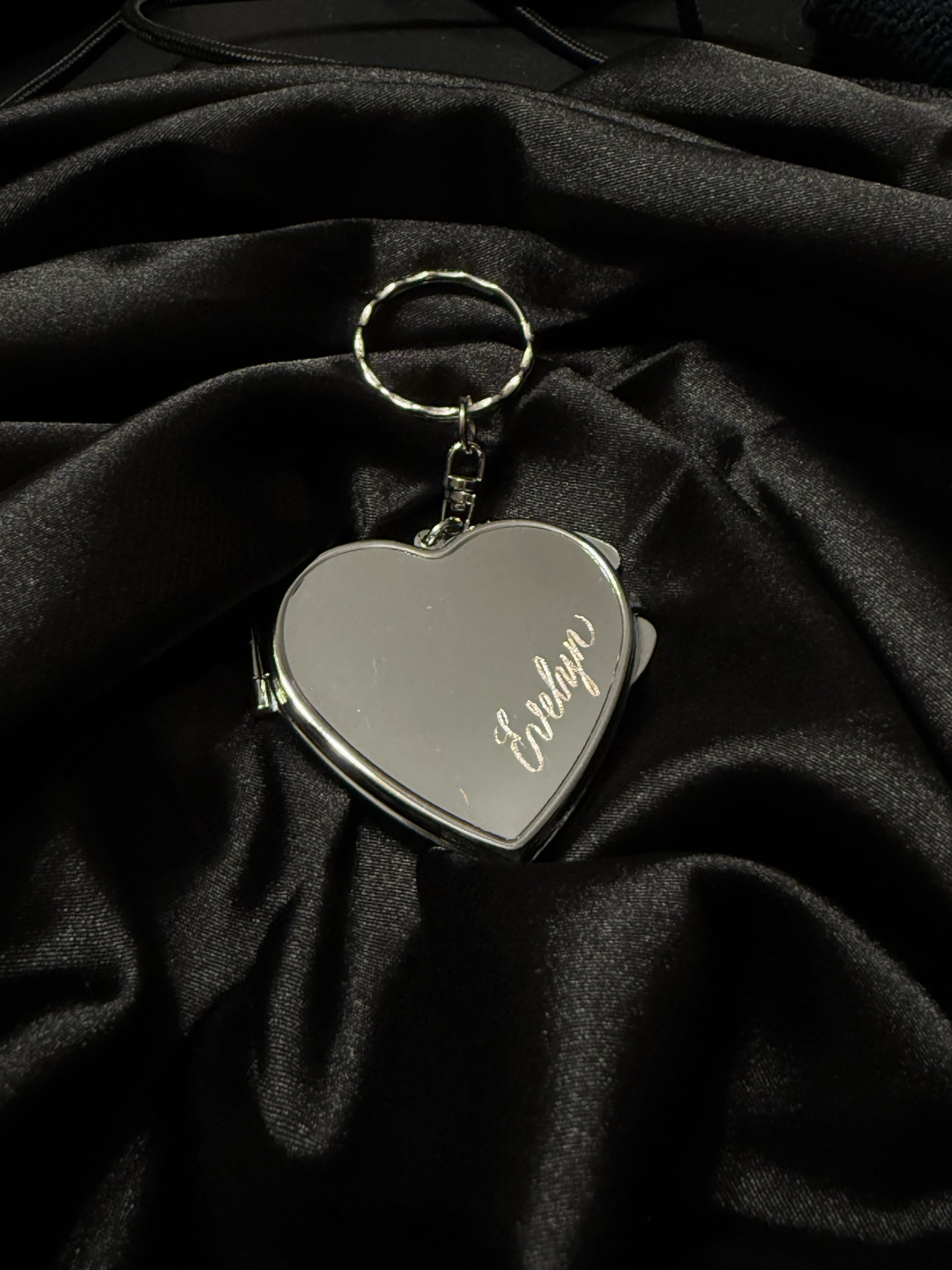 Silver Heart Compact Mirror Keychain engraved with the name "Evelyn" on a black silk background