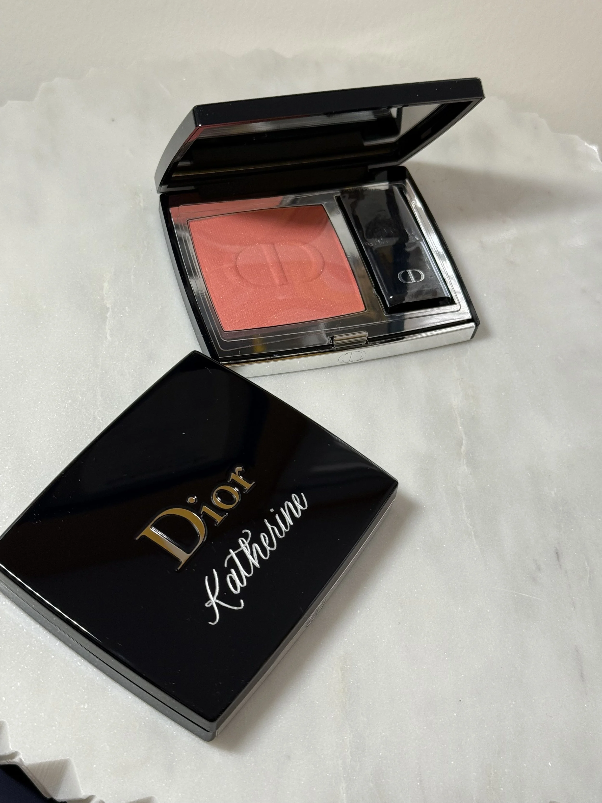 2 Dior blushes, one open, one closed showing an engraved name in silver calligraphy