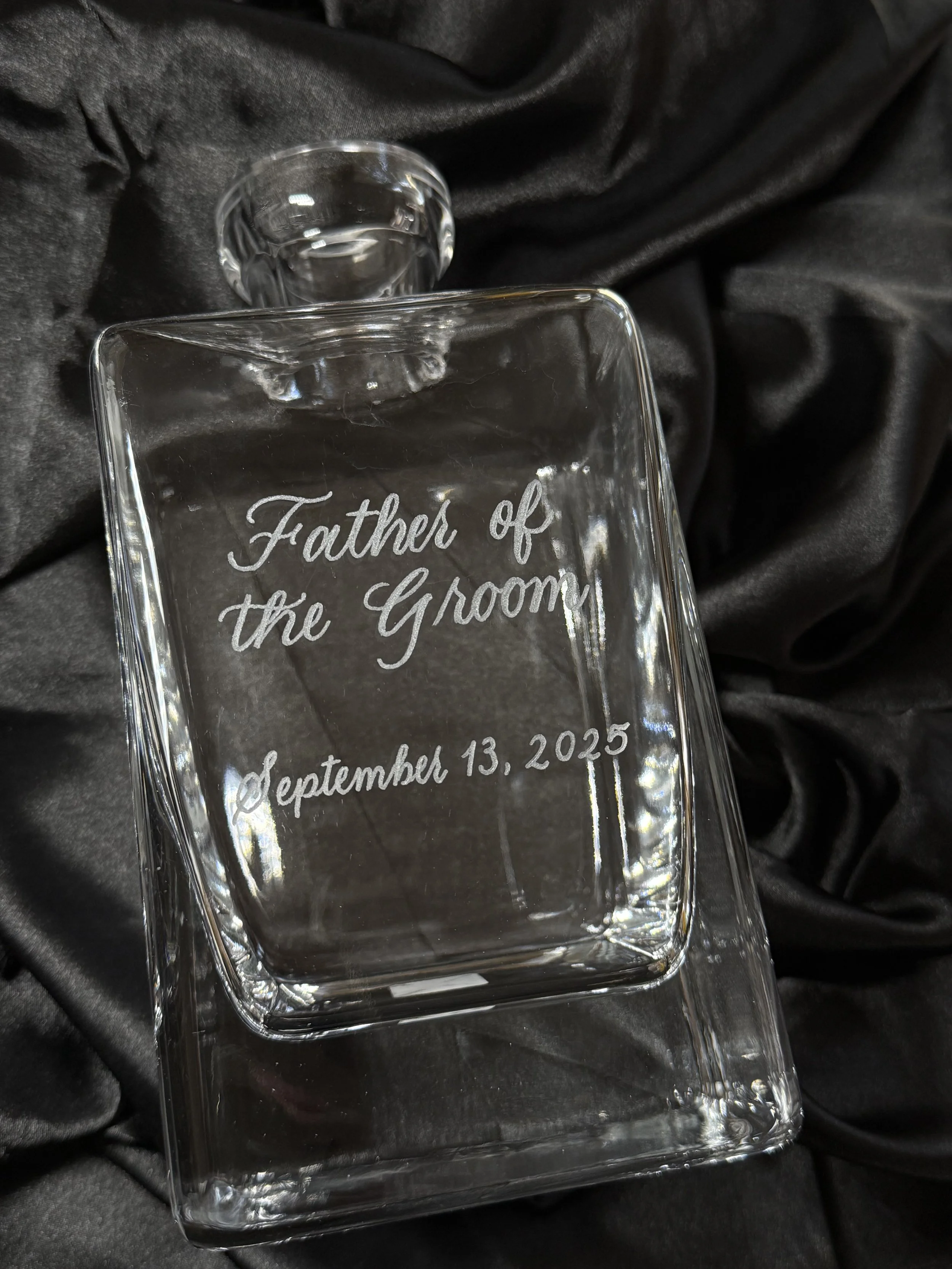 Glass Liquor decanter engraved with "Father of the Groom" in silver calligraphy with date below on a black satin background