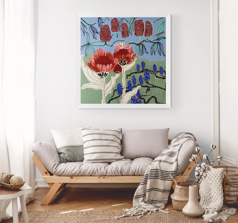 A colorful abstract floral painting hangs above a beige sofa with striped pillows in a bright living room.