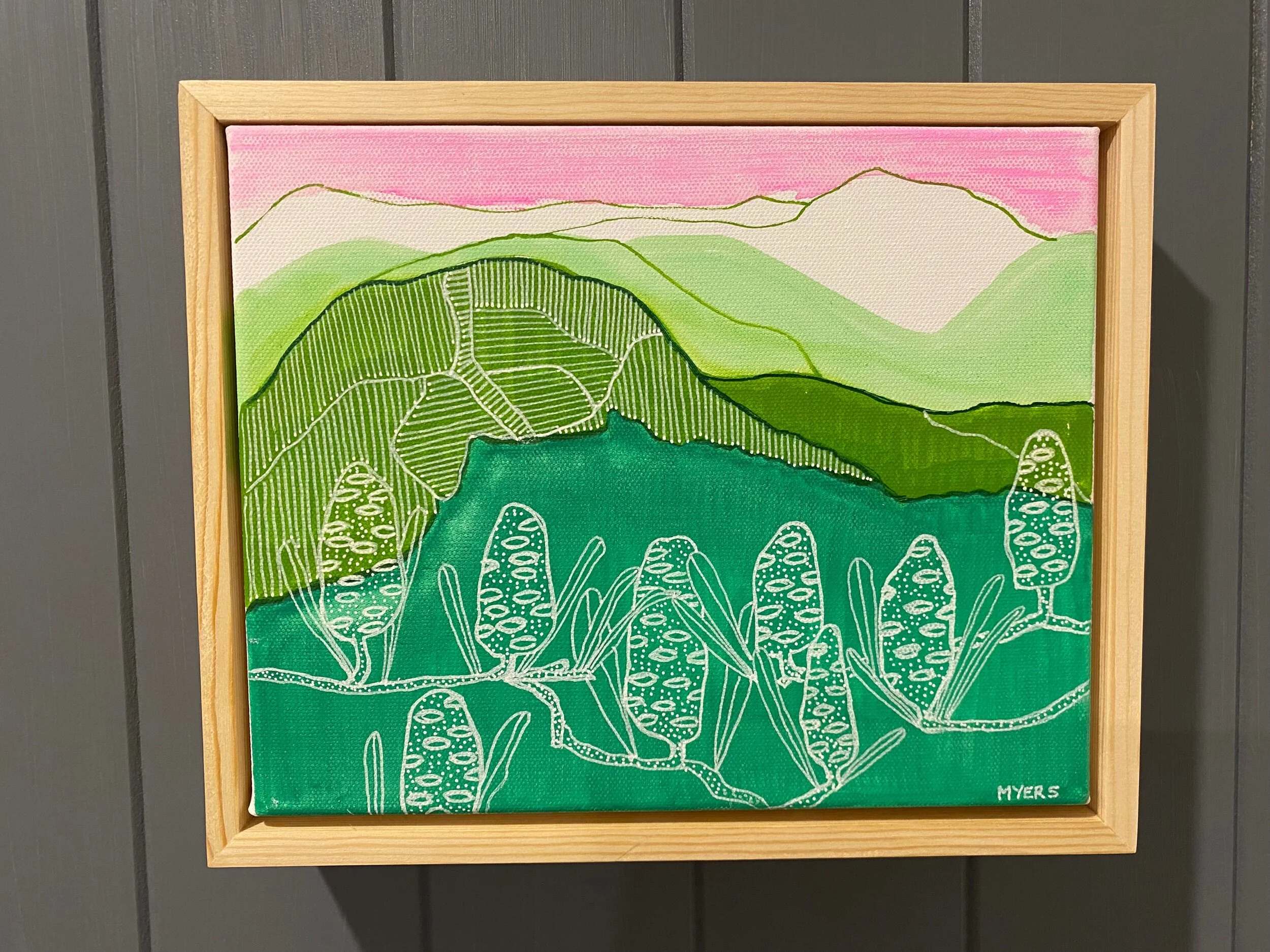 Colorful abstract landscape painting with green hills, pink sky, and stylized plants in a wooden frame.