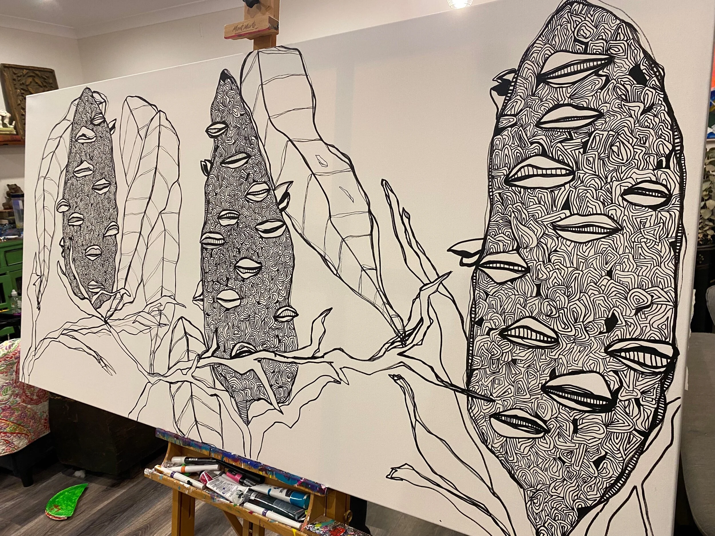 A large canvas features an abstract black and white line drawing of a landscape with tall, textured rock formations and large leaves, some of which have stylized lips and eyes.