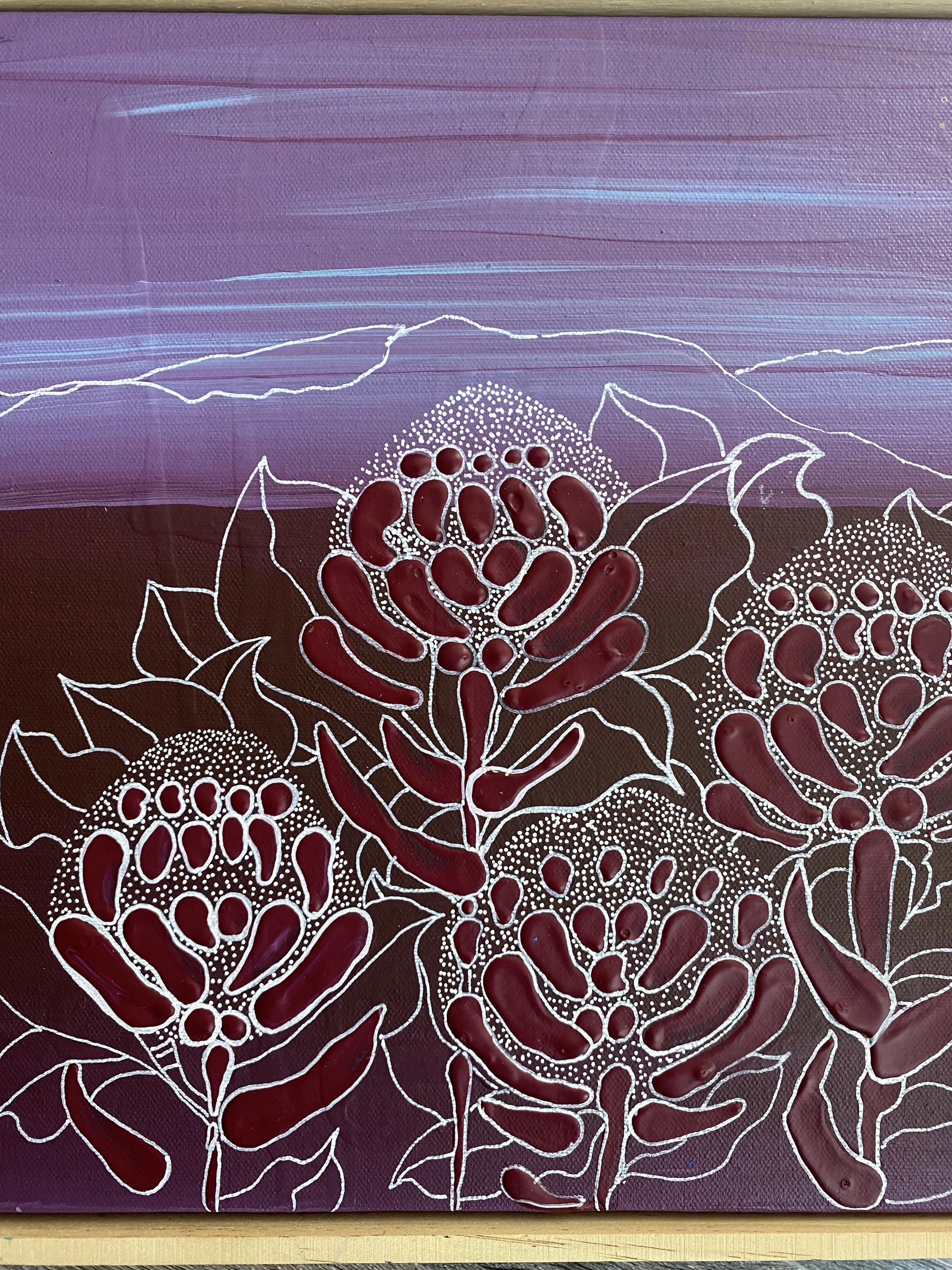 Painting of large flowers with dark red and black petals, outlined in white, set against a purple and pink background with mountain and sky details.