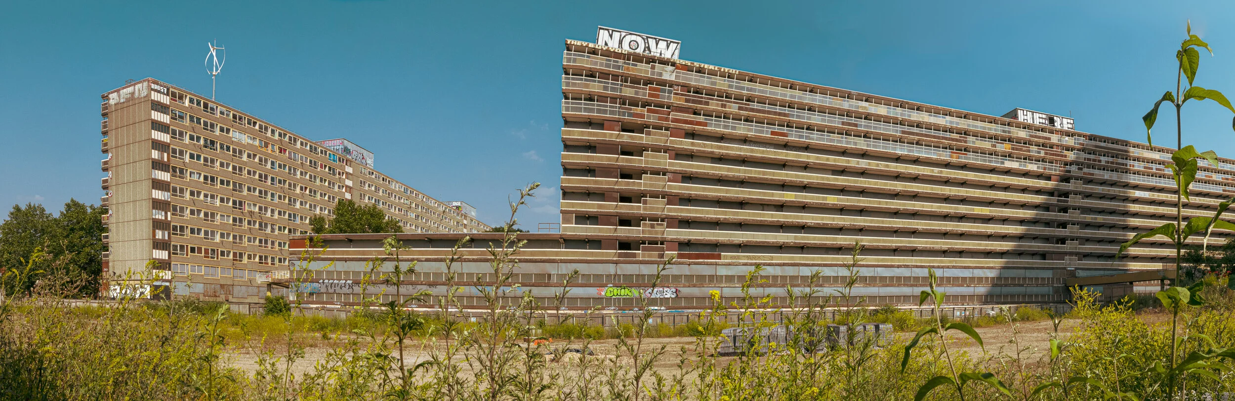 Panorama of the long concrete blocks of the Heygate Estate above overgrown wasteland, Elephant and Castle, in summer 2013