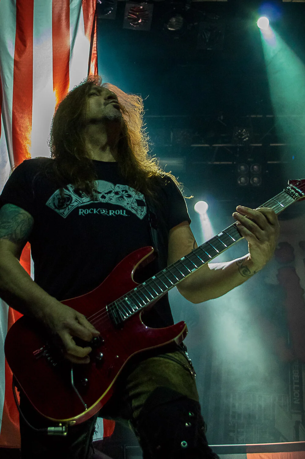 Dave “Snake” Sabo playing a red guitar in front of a US flag, Skid Row live in concert at The O2 Forum Kentish Town, January 2019
