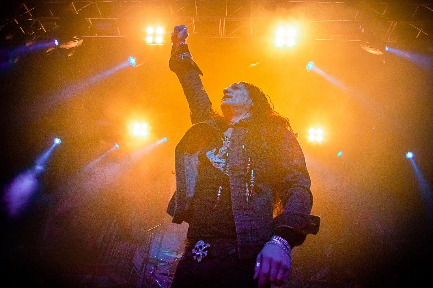 ZP Theart of Skid Row raising a fist on stage, lit by orange spotlights at the O2 Forum Kentish Town