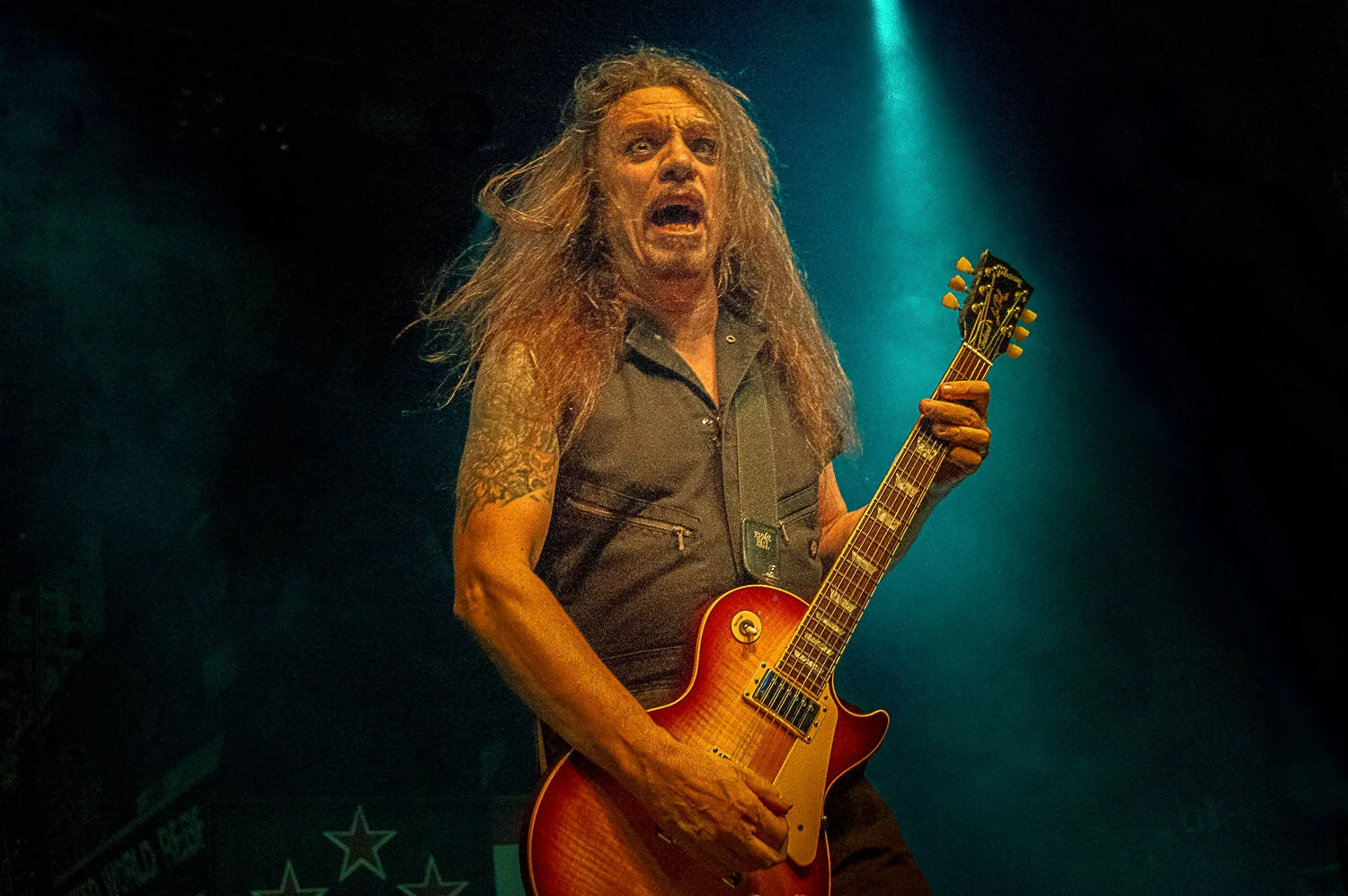 Scotti Hill playing a sunburst Les Paul under green and blue light, Skid Row live in concert at The O2 Forum Kentish Town, January 2019