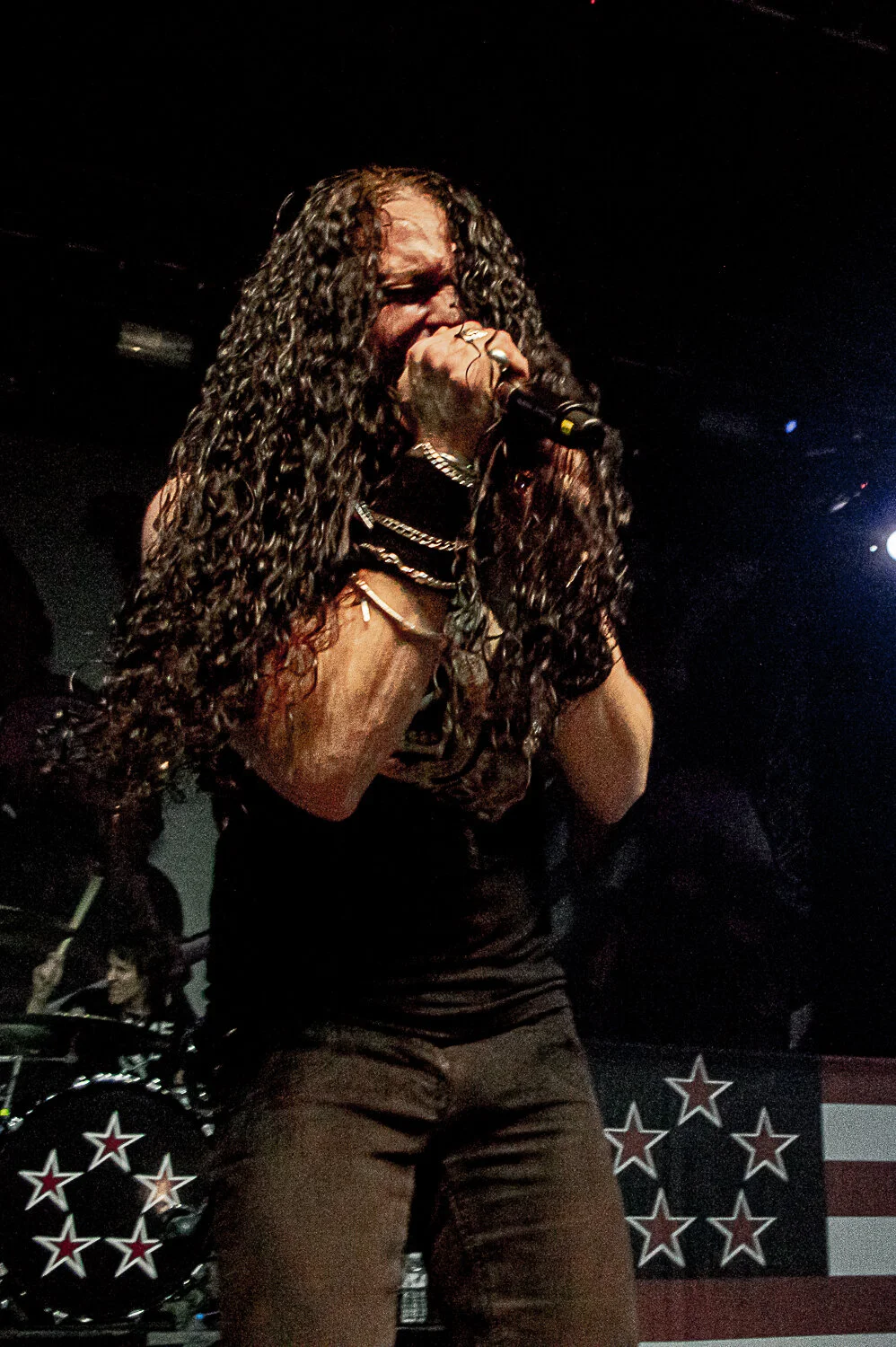 ZP Theart singing with both hands on the microphone, stars and stripes drum kit behind, Skid Row live in concert at The O2 Forum Kentish Town, January 2019