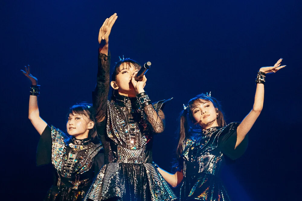 Su-metal of Babymetal singing with one arm raised under blue stage light, live at The O2 Academy Brixton