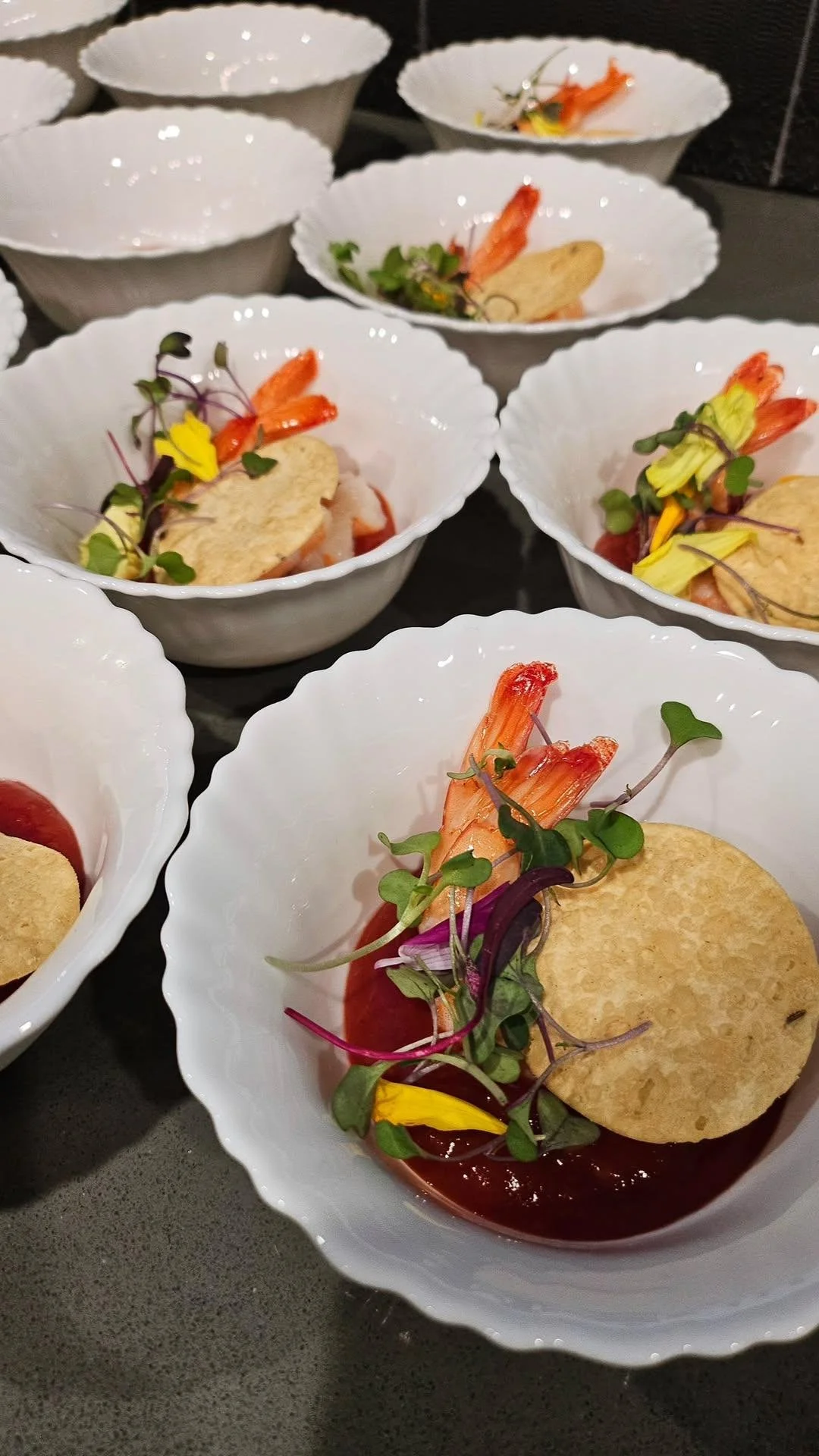 Appetizer dishes with prawns, microgreens, and chips in white bowls.
