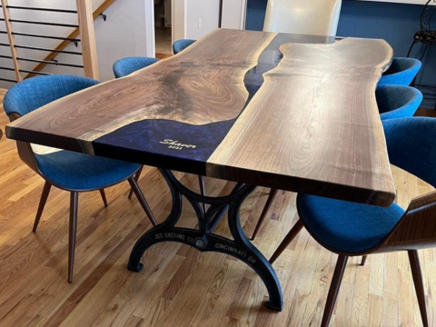 JCS Casting Co. cast iron dining table base supporting a live-edge walnut and epoxy resin table top with blue chairs