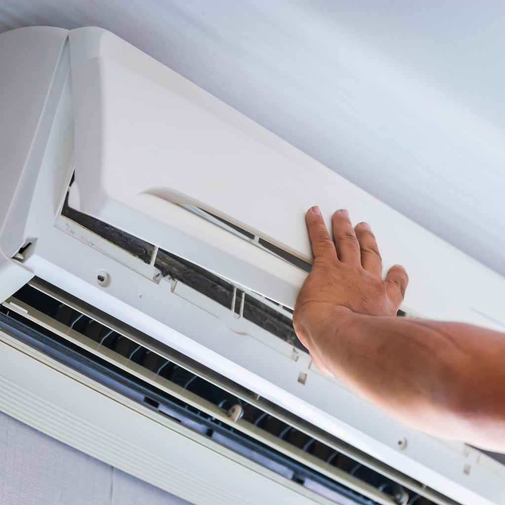 Person inspecting or cleaning the inside of an air conditioning unit.