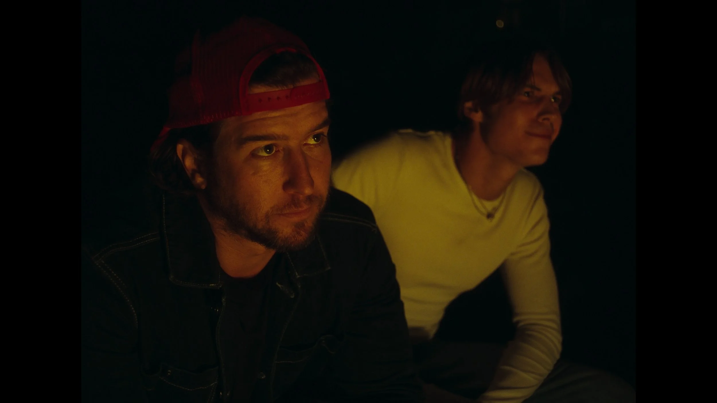 cinematic still frame from indie film, Openers, two men sit at a fire pit, glowing from the warm light of the fire