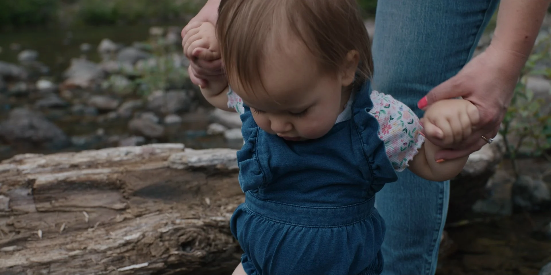 Frame grab from tourism campaign for Discover Lewis County, with the help of mom's hands to keep them standing a toddler splashes in a river