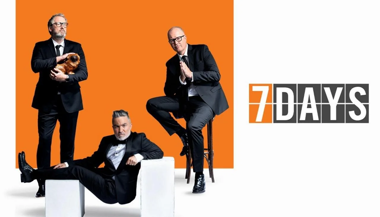 Three men in black suits posing against an orange background with the text '7 Days'.