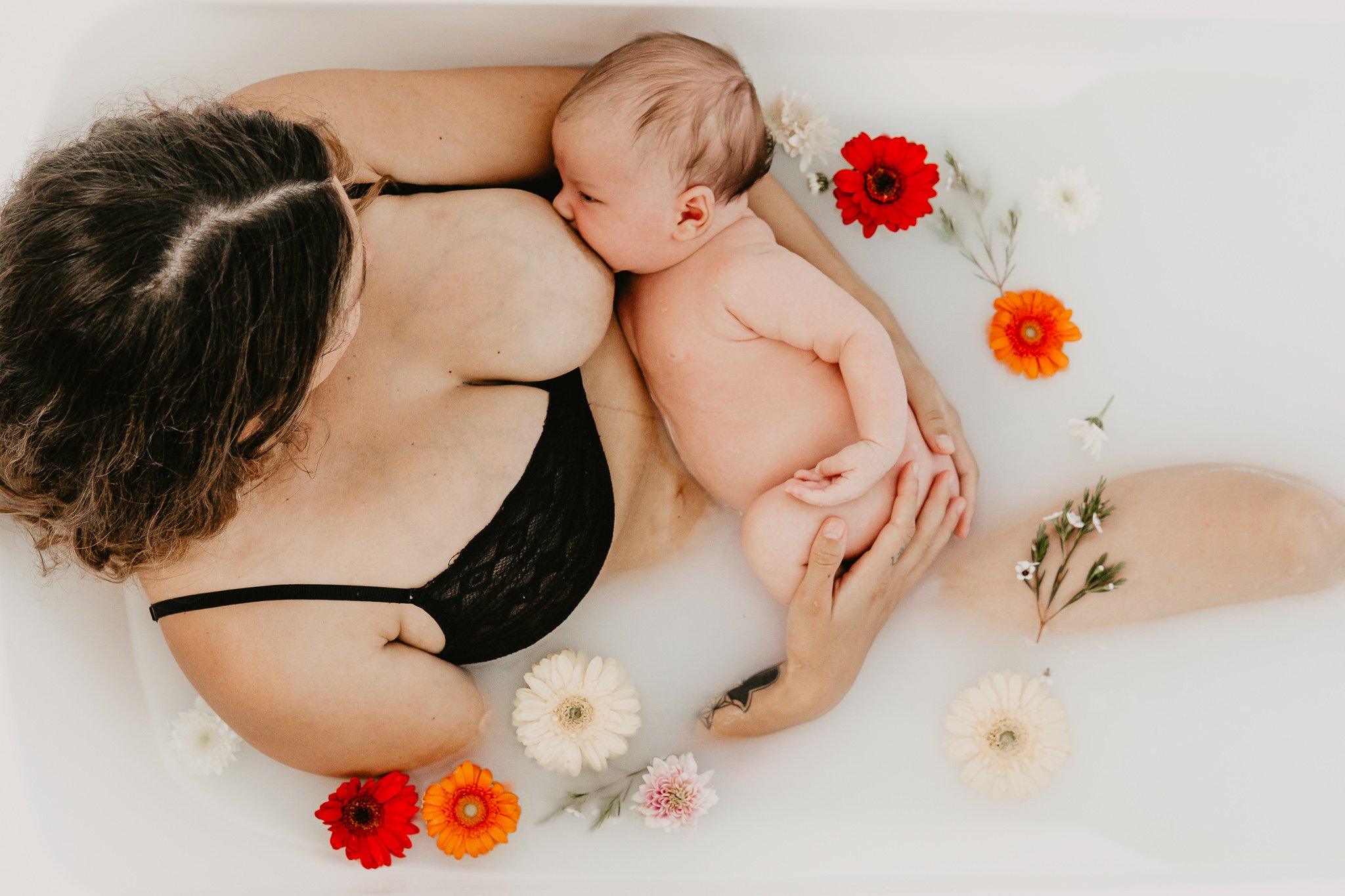mum breastfeeding a newborn in a floral bath.jpg