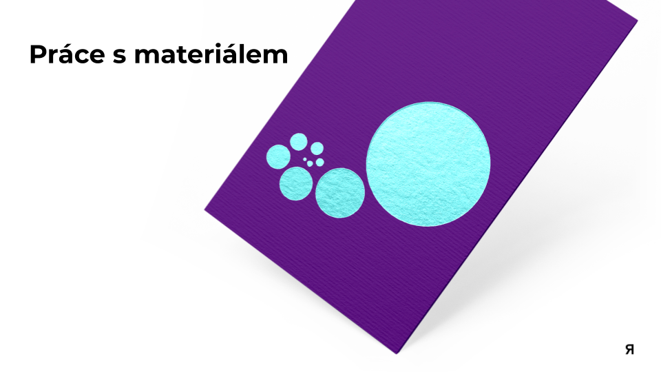 A purple textured foam sheet with blue paper cutouts of circles of different sizes. The text 'Práce s materiálem' is in the top left corner, and there is a small Russian letter 'Я' in the bottom right corner.