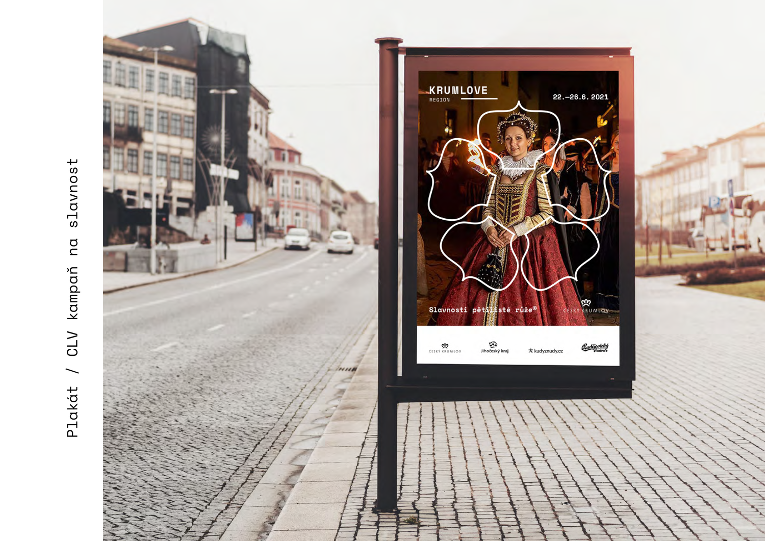 An outdoor view of a city street with a digital billboard displaying a woman in traditional dress, surrounded by white outline flower patterns, and event details in Czech.
