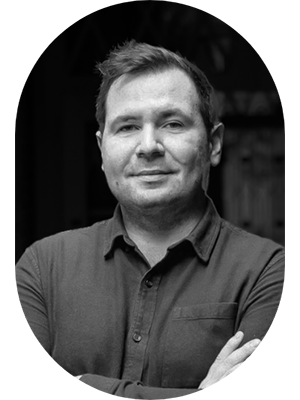 Black and white portrait of a man with short hair, smiling, wearing a collared shirt with arms crossed.