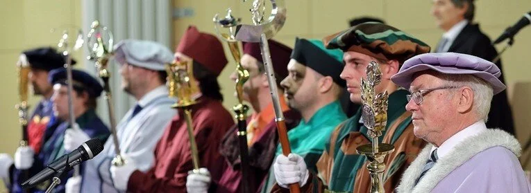 A group of individuals in academic regalia holding ceremonial staffs during a formal event or graduation ceremony.