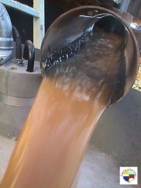 L'eau brune s'écoule d'une tuyère en métal incluse dans un environnement industriel.