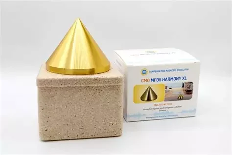 Dispositif de thérapie magnétique avec cône doré sur une base en béton et boîte d'emballage à côté.