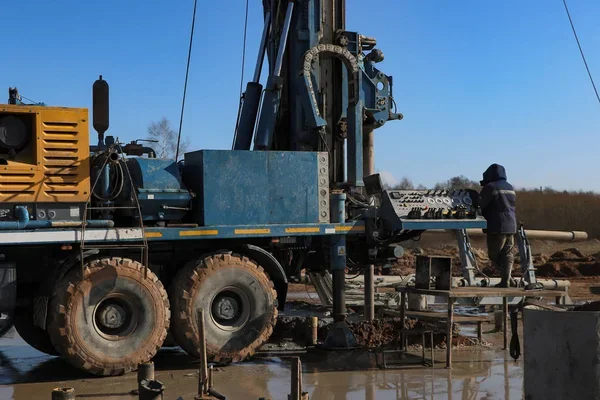 Travail de forage avec une machine lourde sur un chantier en plein air.
