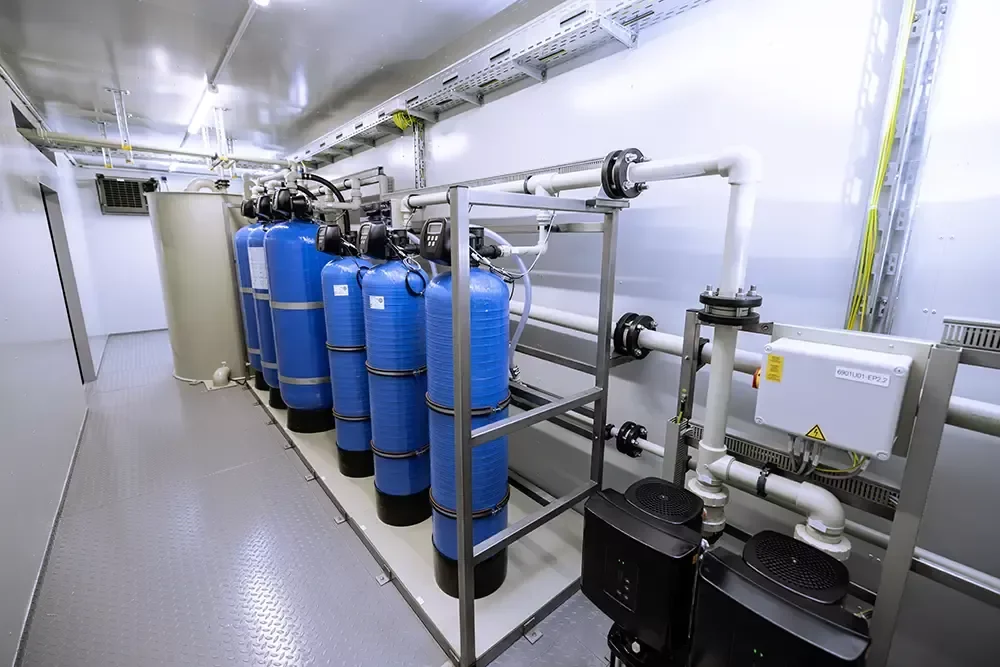 Système de filtration d'eau avec plusieurs cylindres bleus dans une pièce blanche.