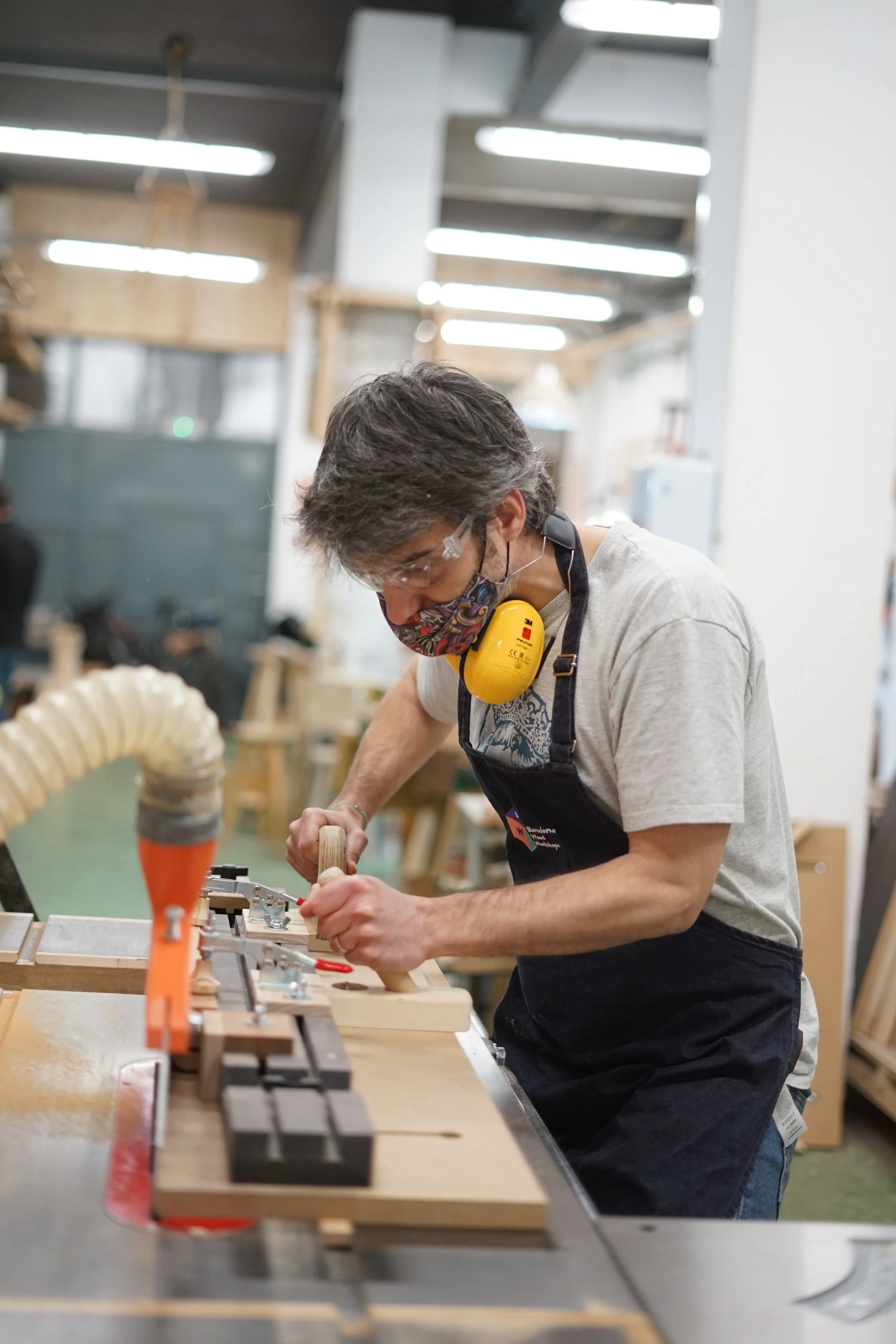 Alumno concentrado realizando un corte en la sierra de mesa del curso de fabricación del taburete en Barcelona.