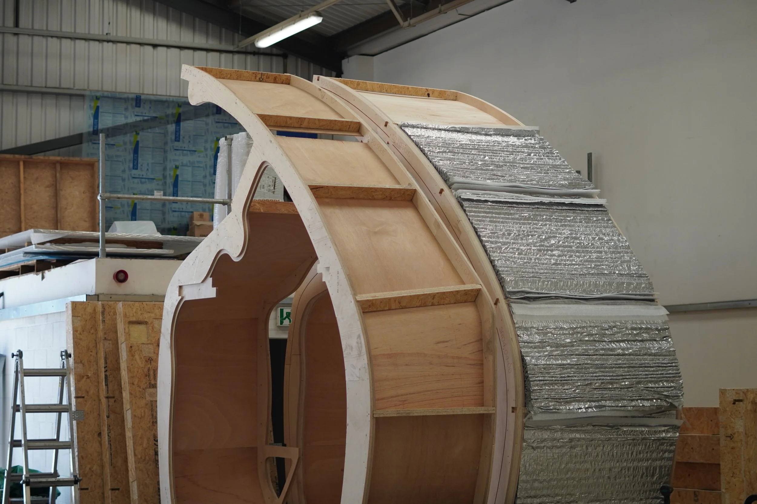 Timber holiday cabin under construction showing layered insulation within the building envelope to reduce heat loss and improve thermal performance.
