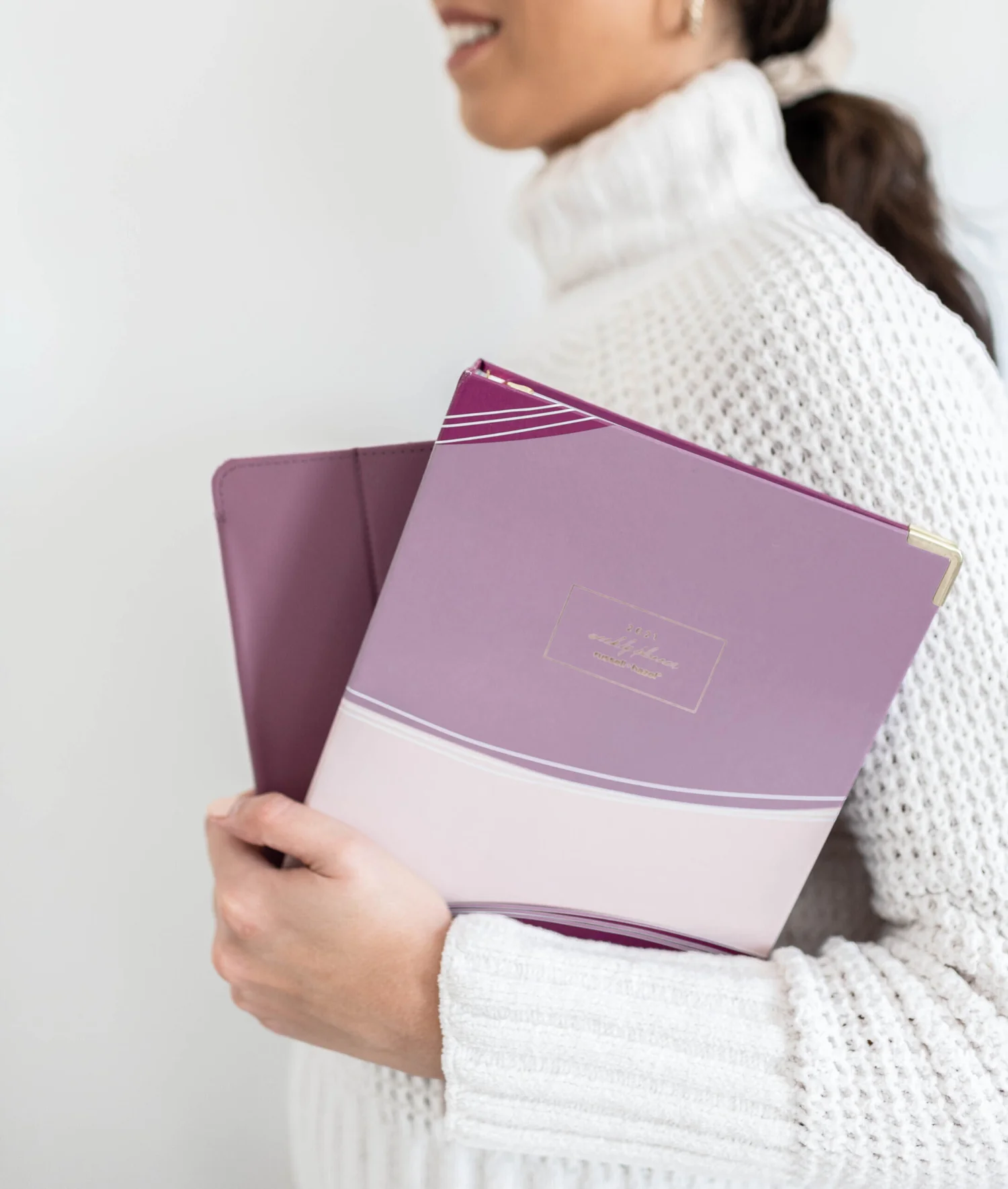 A person holding purple notebooks and a folder