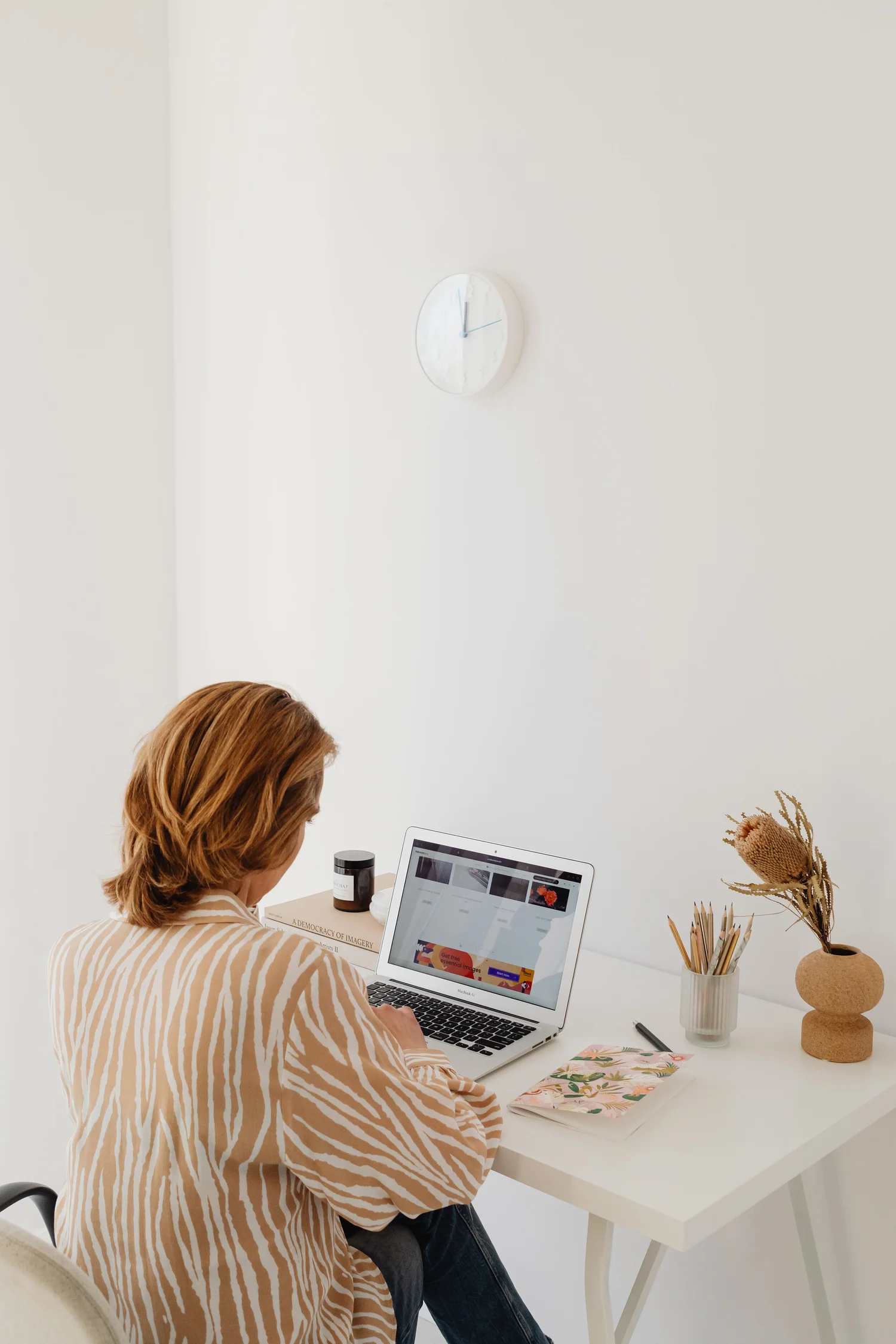 A person working at a laptop on a bright home-office desk