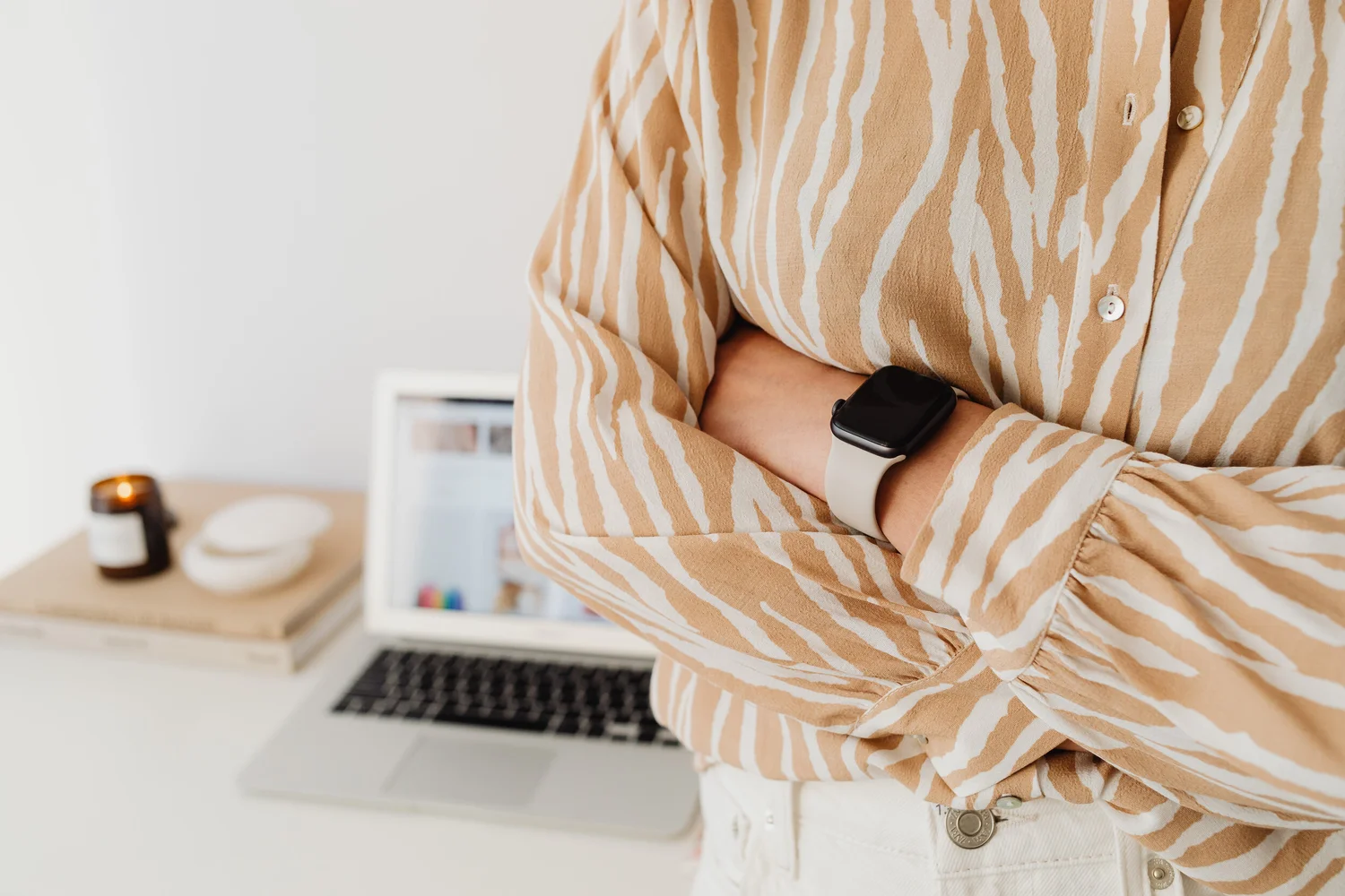 Laptop on a desk beside a person wearing a smartwatch