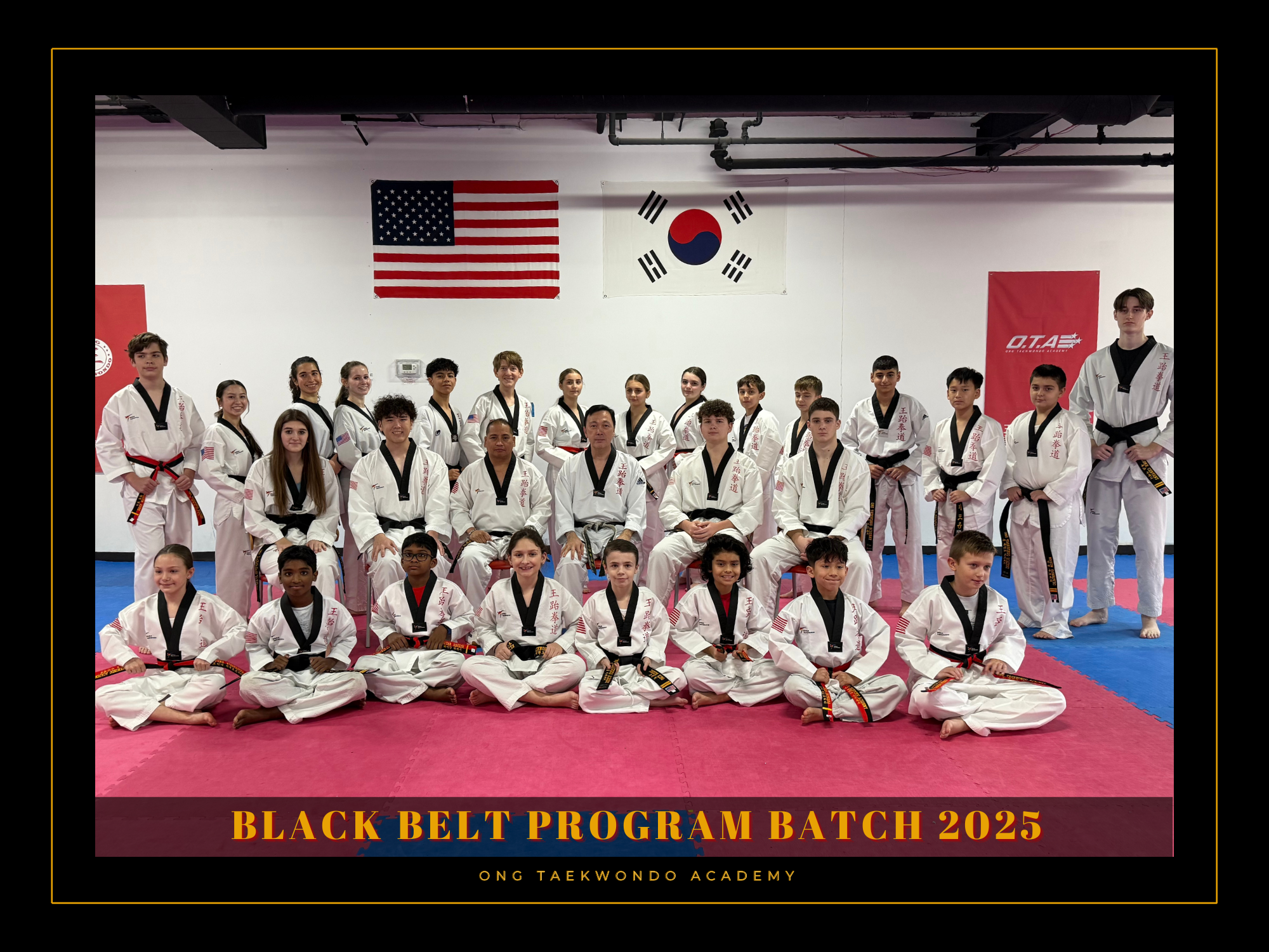 Group of martial arts students and instructors posing in a dojo with American and South Korean flags hanging above. Caption reads "Black Belt Program Batch 2025" and "Ong Taekwondo Academy."
