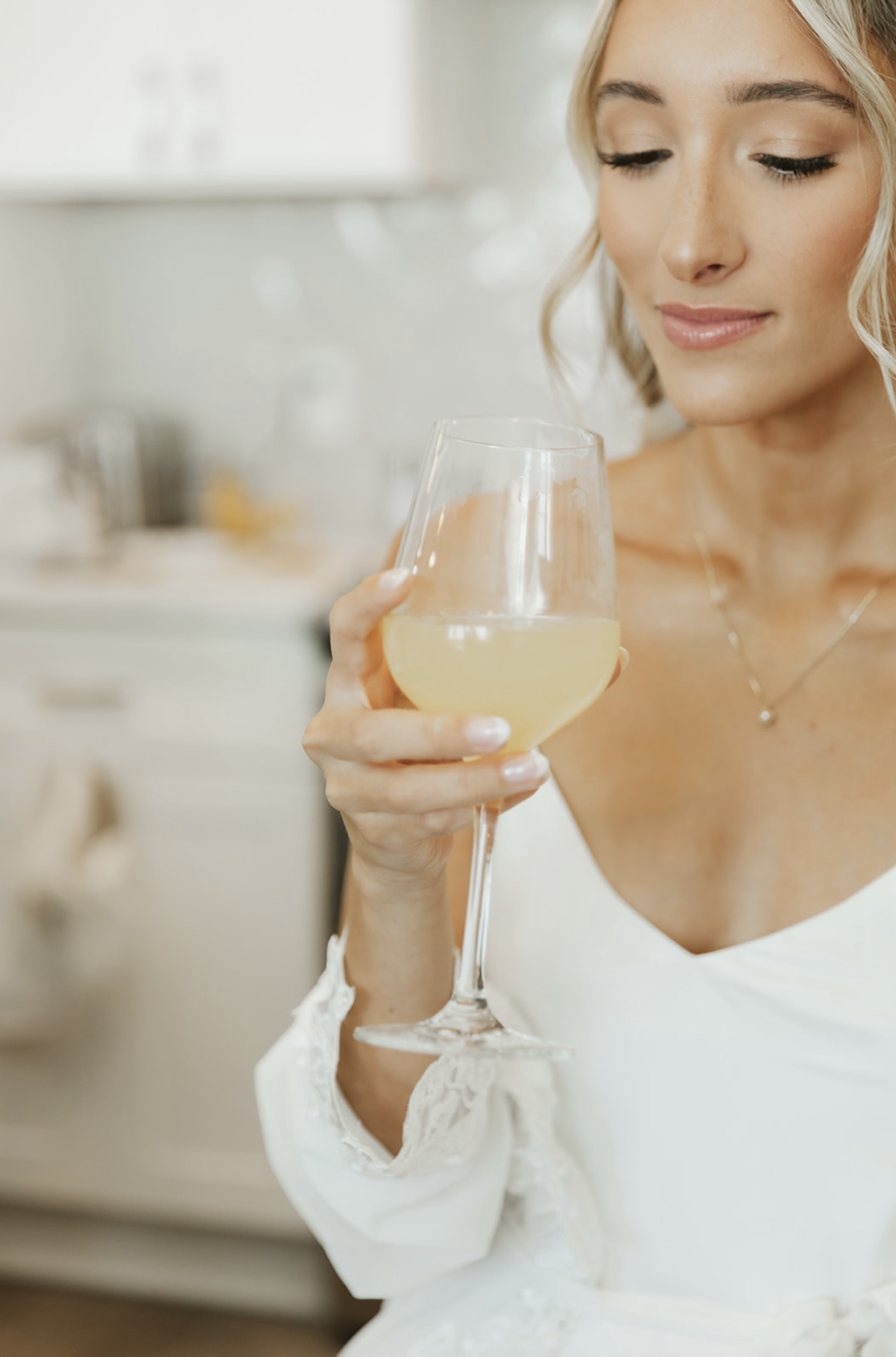 Woman holding a glass of white wine in a kitchen