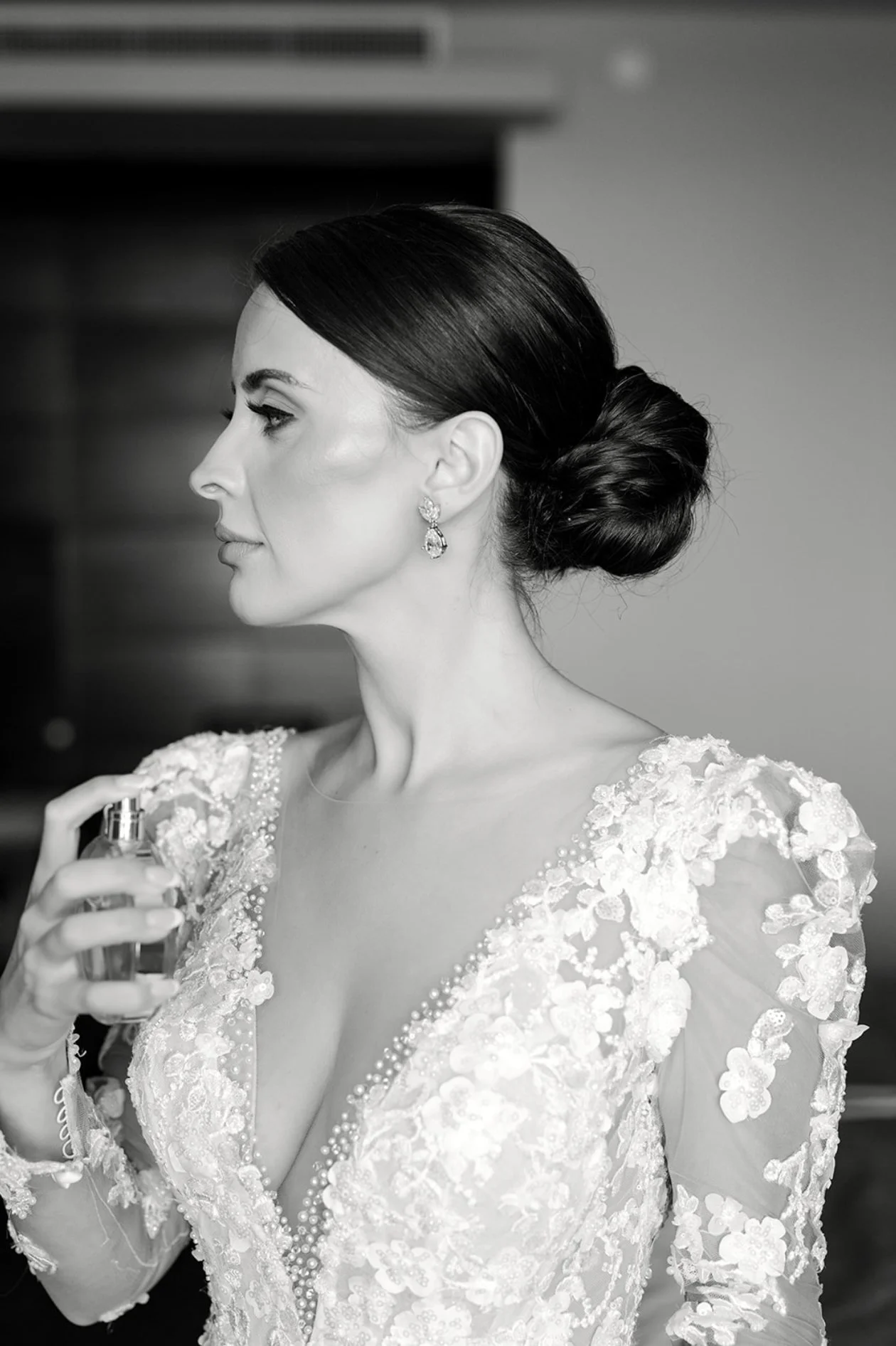 Bridal hair and makeup by Tania Crawford: bride with a sleek low bun spritzing perfume, black and white